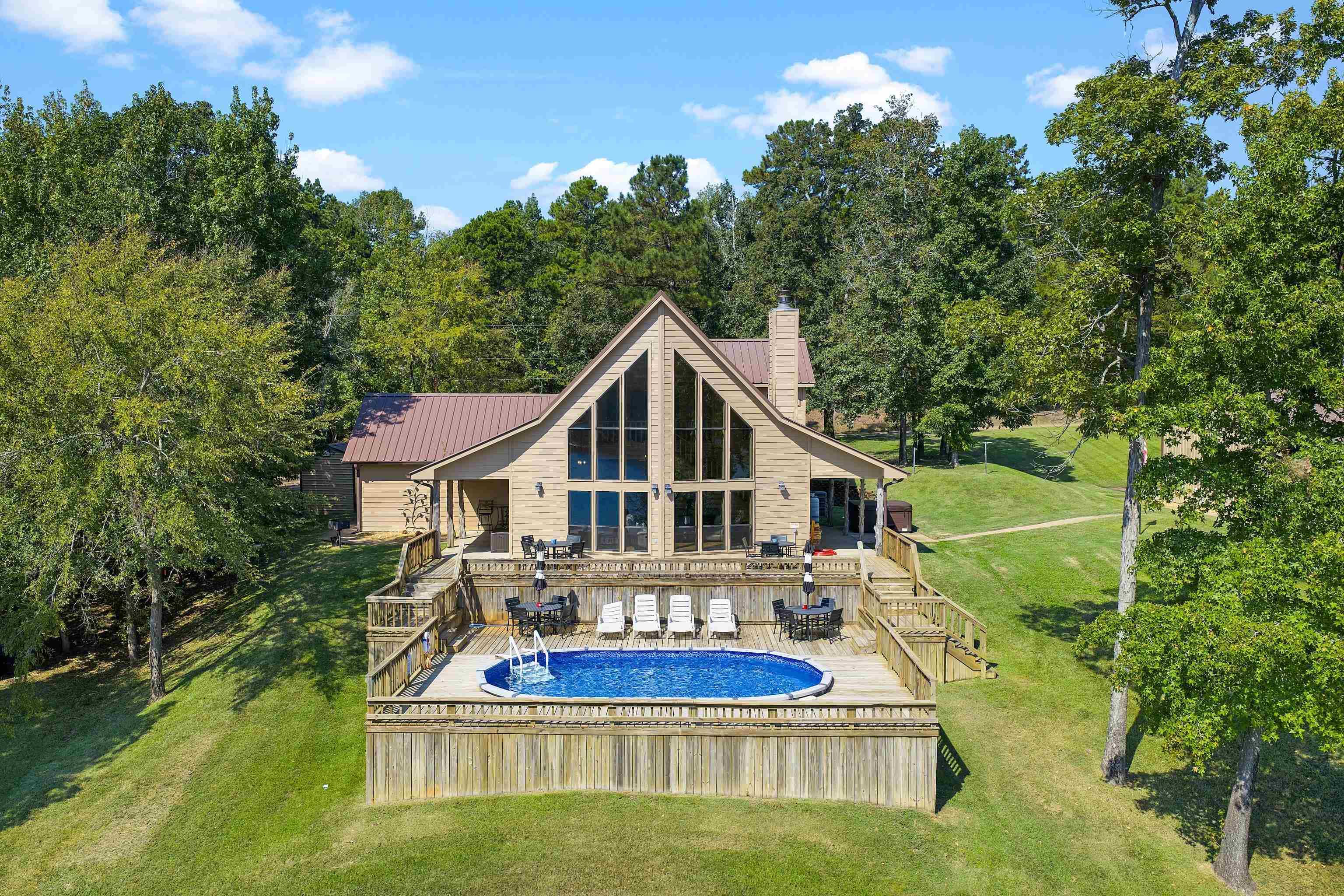 Image 3: Outdoor pool featuring a yard, a deck, and a forest view, Large Home View