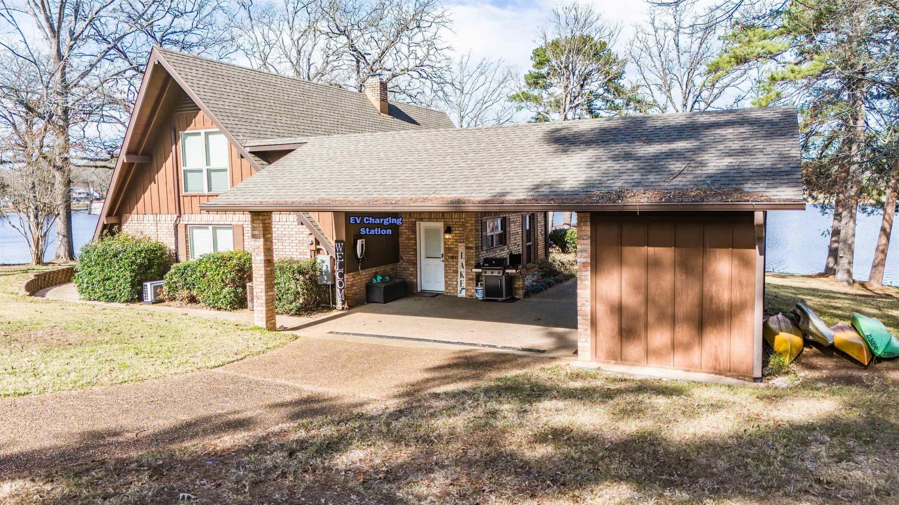 Image 1: View of front of property with board and batten siding, a shingled roof, brick siding, and a front yard, Front Of Structure