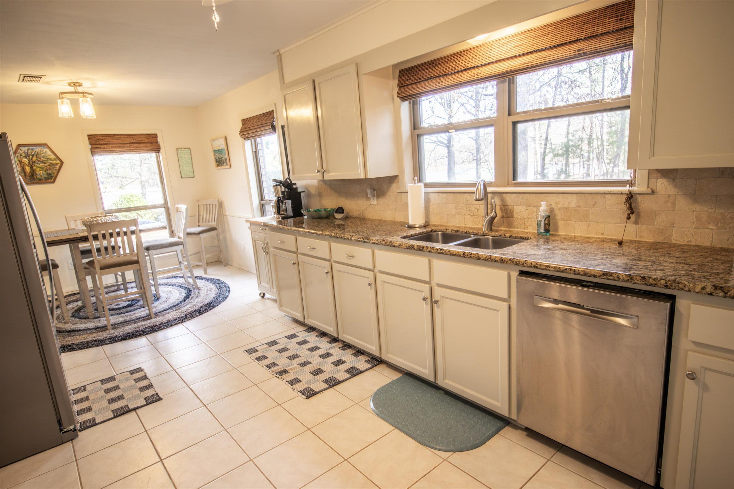 Image 3: Kitchen with appliances with stainless steel finishes, dark stone counters, light tile patterned floors, and plenty of natural light, Kitchen