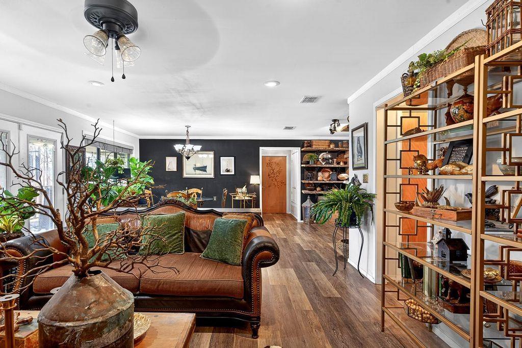 Image 2: Living room with dark wood-type flooring, ornamental molding, a ceiling fan, and suspended lighting, Main Living Room