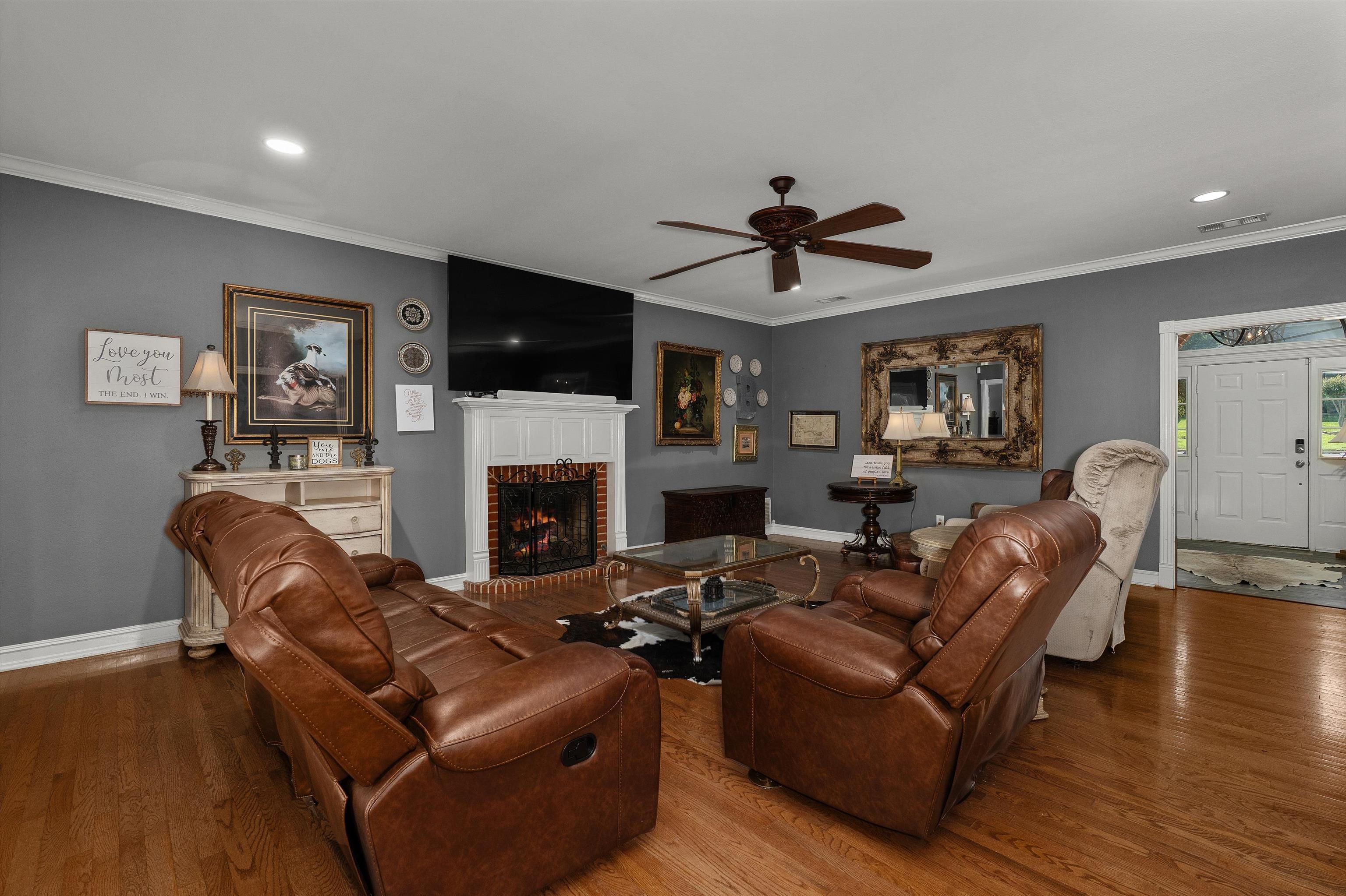 Image 3: Living area featuring wood-finish flooring, a white mantel fireplace, crown molding, and recessed lighting, Living Room