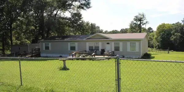 Image 2: Single-story residence featuring light-colored siding and white window shutters, Front Of Structure
