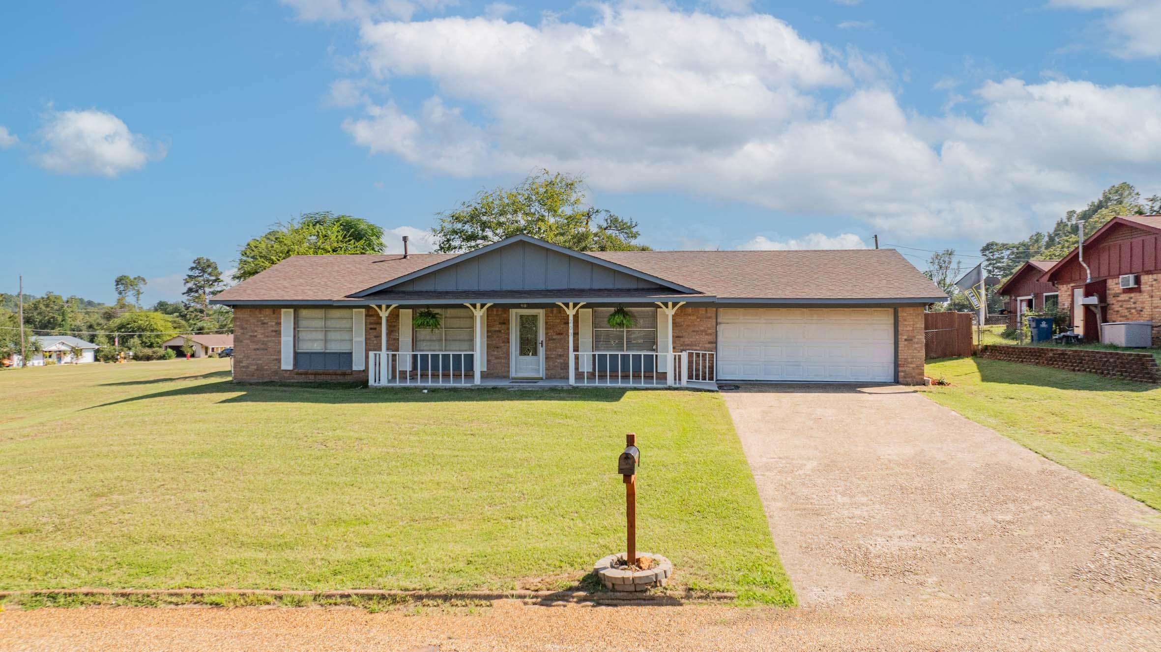 Image 1: Single story home with covered porch, brick siding, and a front lawn, Front Of Structure