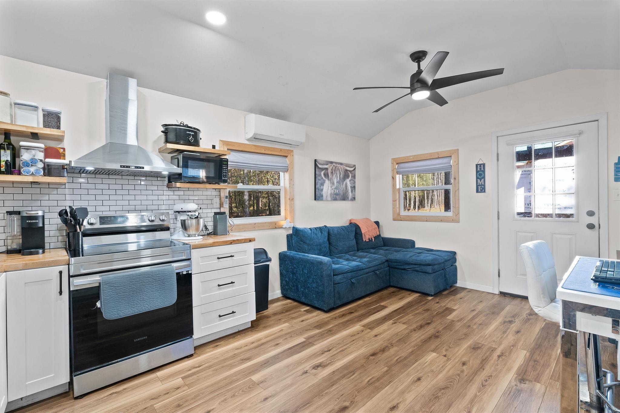 Image 0: Kitchen with white cabinetry, stainless steel electric range oven, vaulted ceiling, open shelves, and wall chimney range hood, Kitchen