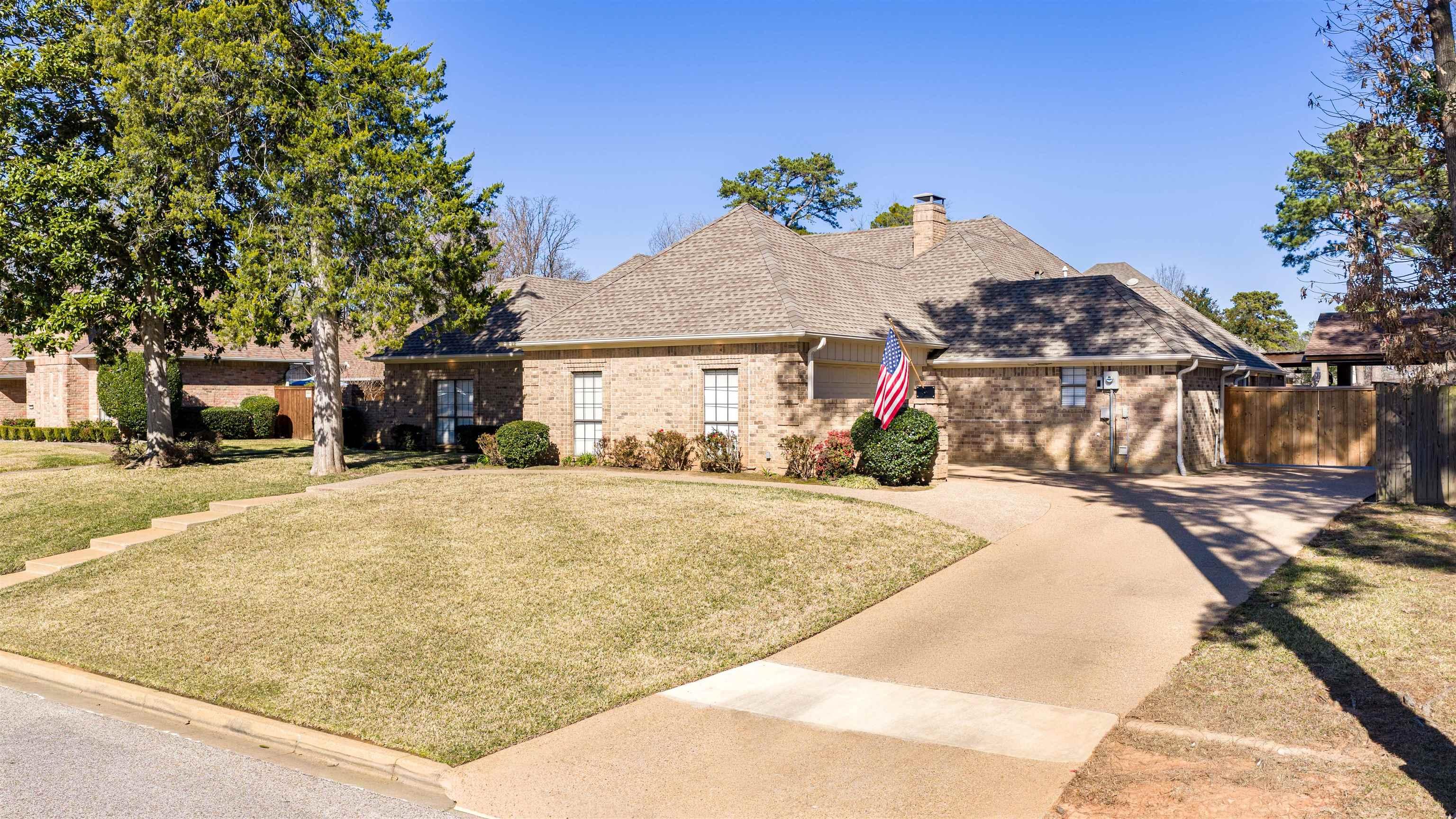 Image 1: View of front of home featuring brick siding, roof with shingles, a chimney, and concrete driveway, Front Of Structure