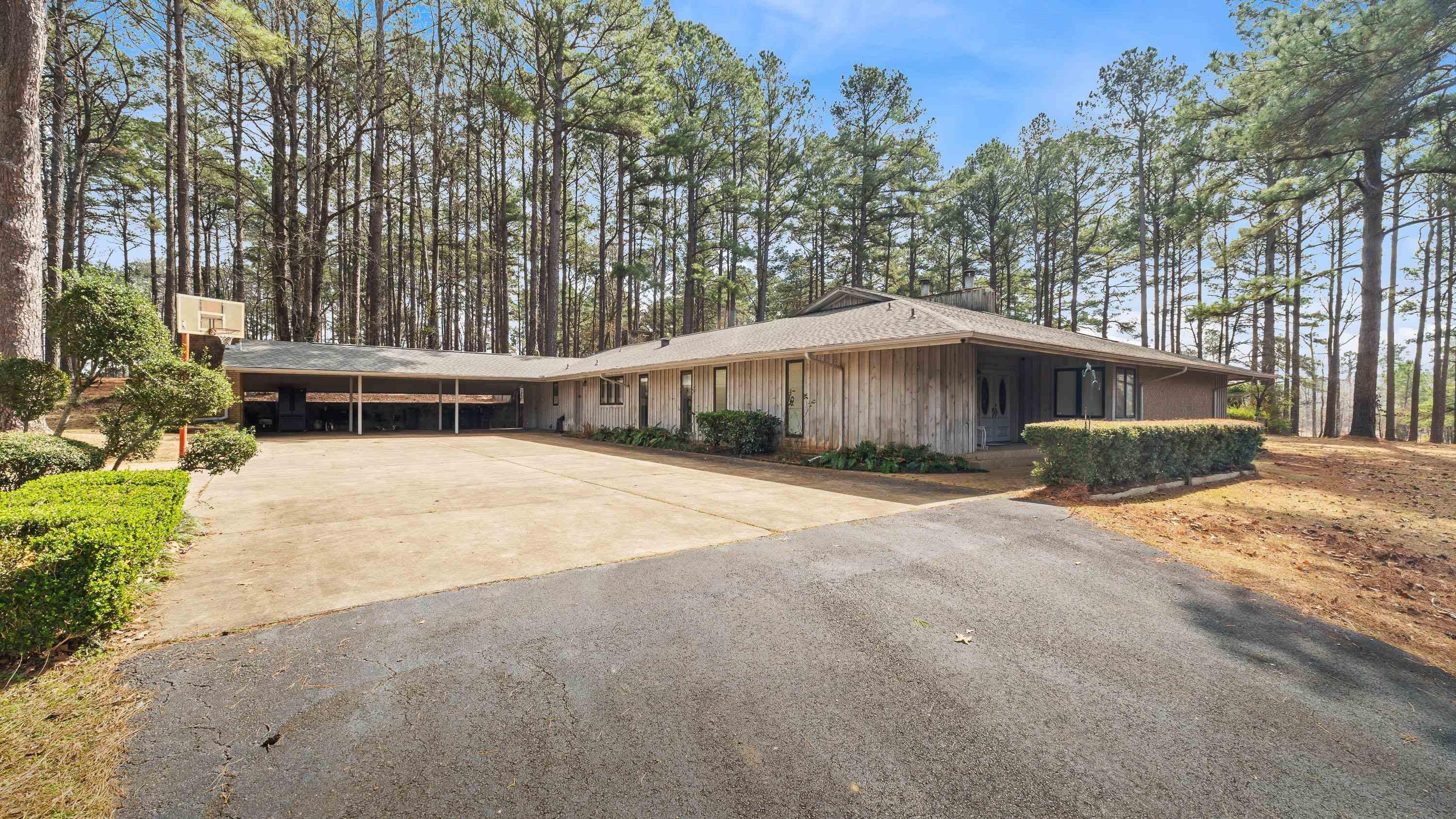 Image 3: View of front facade with board and batten siding, concrete driveway, and an attached carport, Front Of Structure