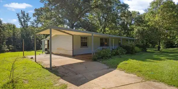 Image 3: White siding residence with a covered carport and a full-length covered porch, Front Of Structure