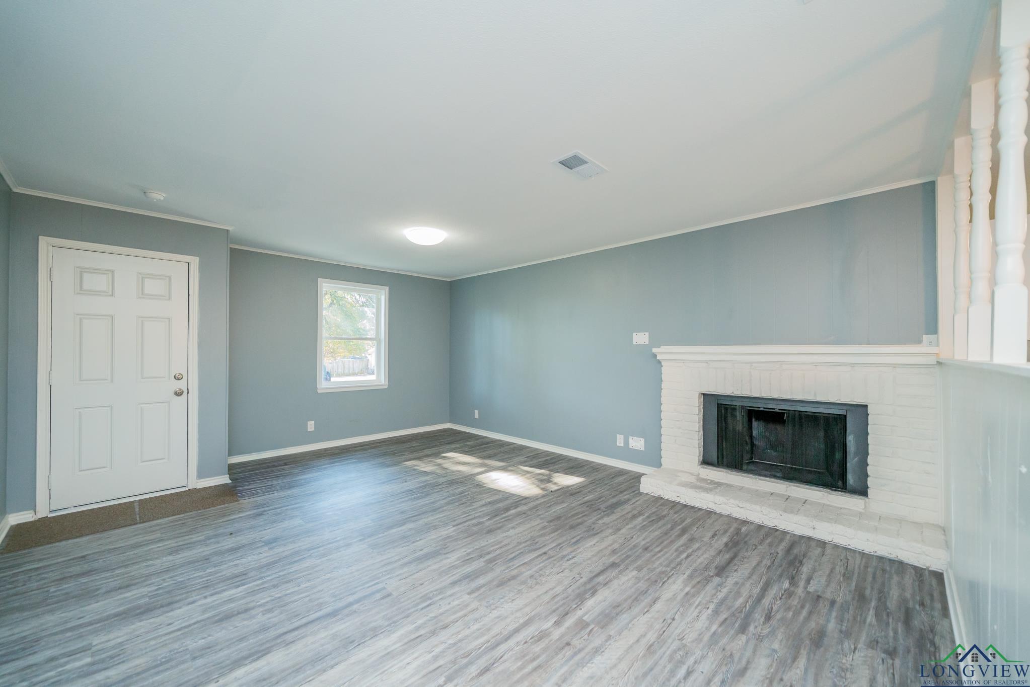 Image 2: Unfurnished living room with ornamental molding, wood finished floors, and a brick fireplace, Living Room