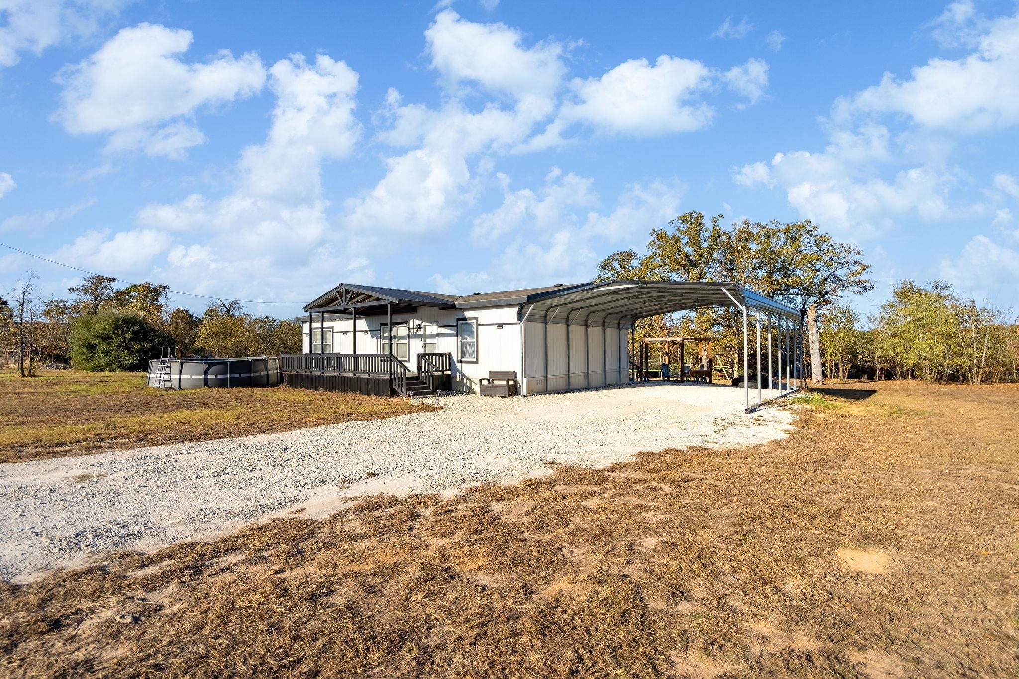 Image 0: View of outdoor structure with driveway and a carport, Front of Home