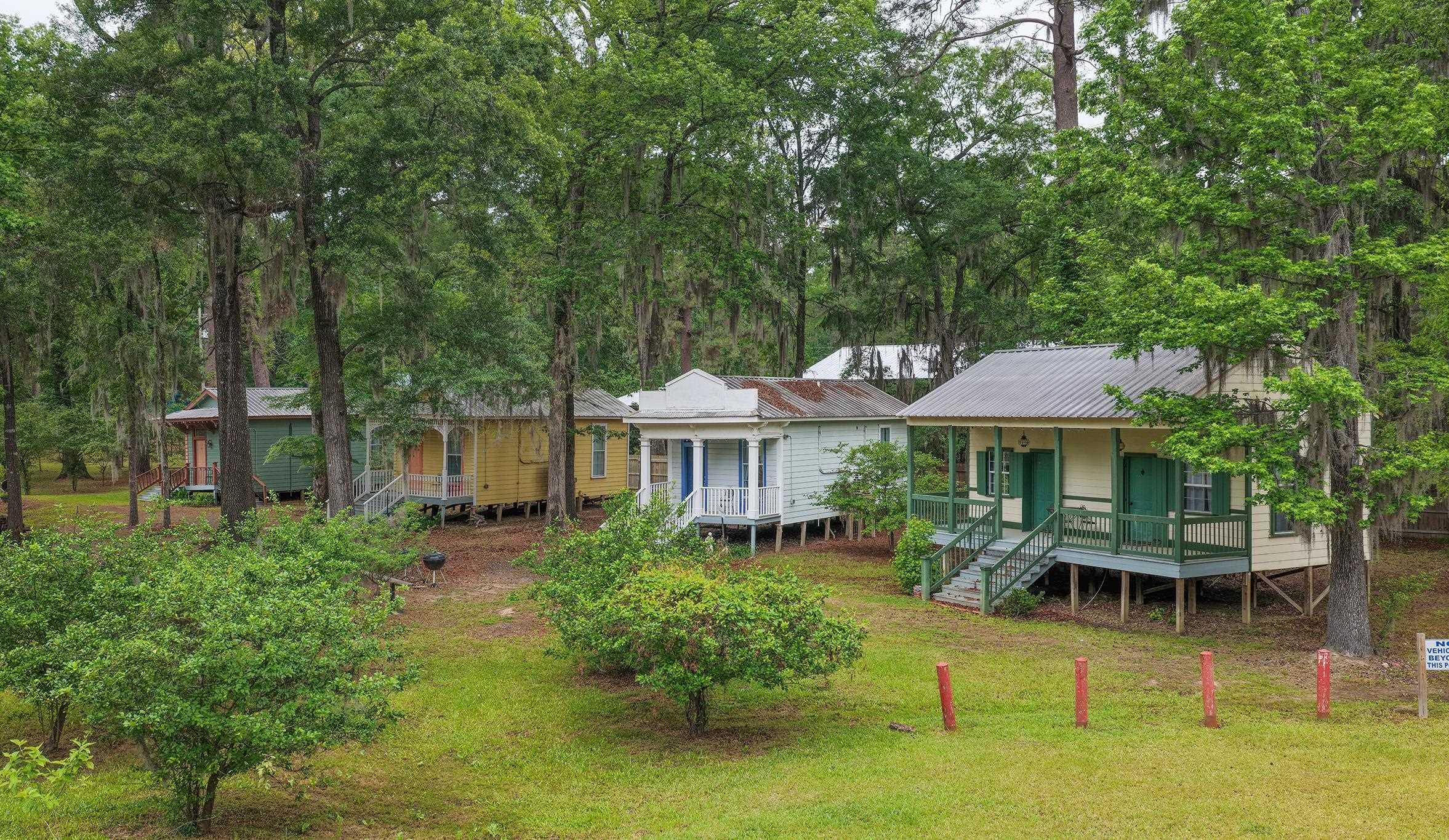 Image 1: Multiple elevated structures with individual covered porches, set amidst mature trees, Sleeping Cabins