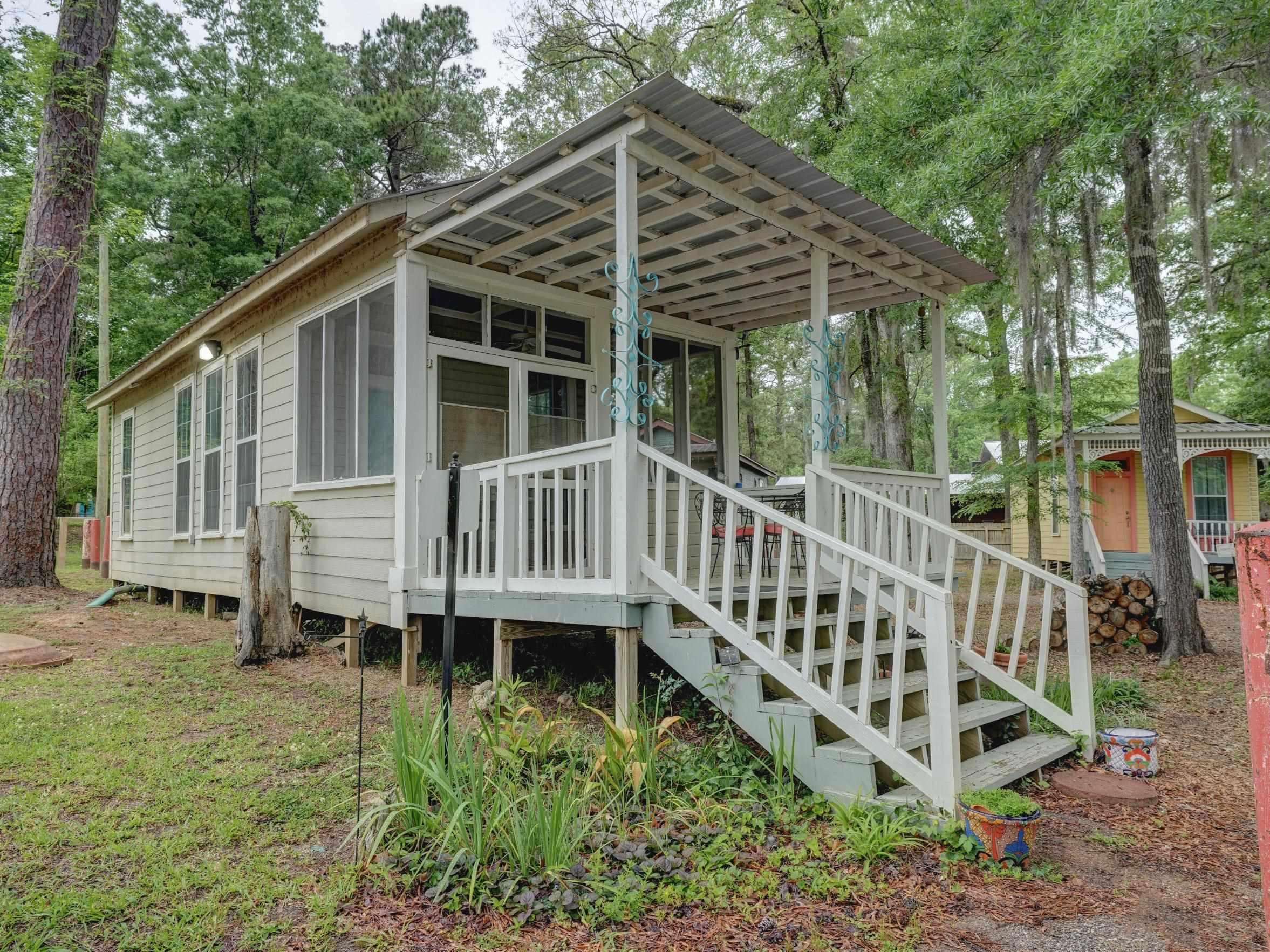 Image 2: Elevated white siding exterior featuring a covered porch with a metal roof, white railing, and screened enclosure, Breakfast Cabin