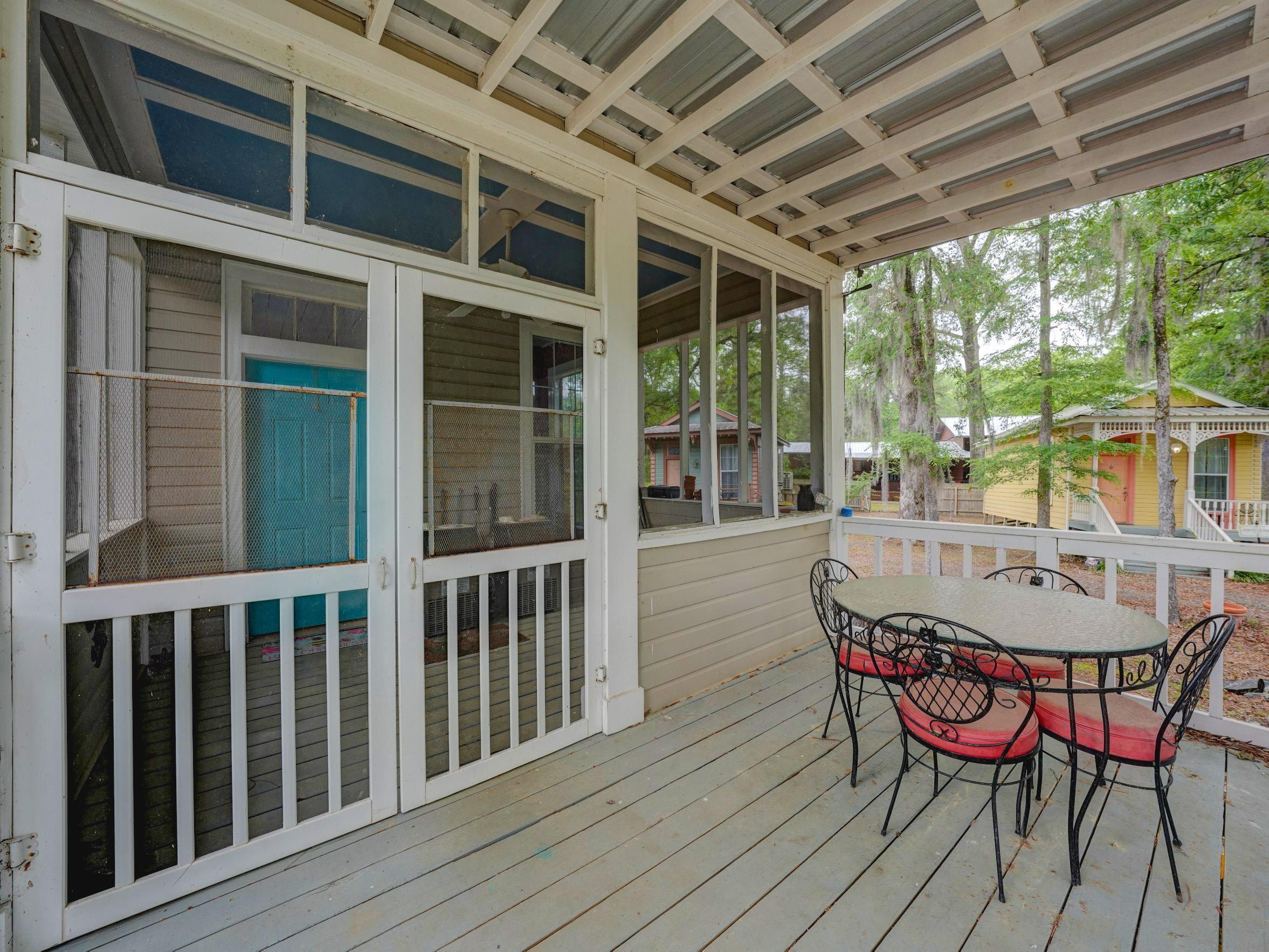 Image 3: Expansive screened porch with wood-finish flooring, white railing, and a corrugated metal ceiling, Breakfast-Deck