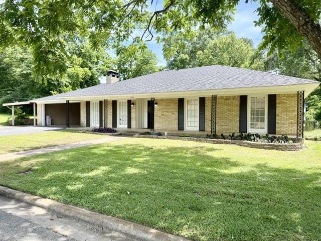 Image 0: Ranch-style residence featuring a light brick exterior, dark shingles, and a covered carport, Front Of Structure