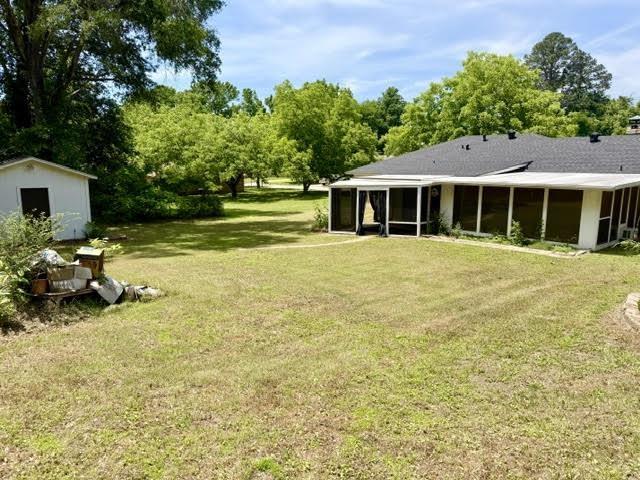 Image 3: Spacious backyard featuring a screened-in patio, mature trees, a detached storage shed, and a privacy fence, Yard