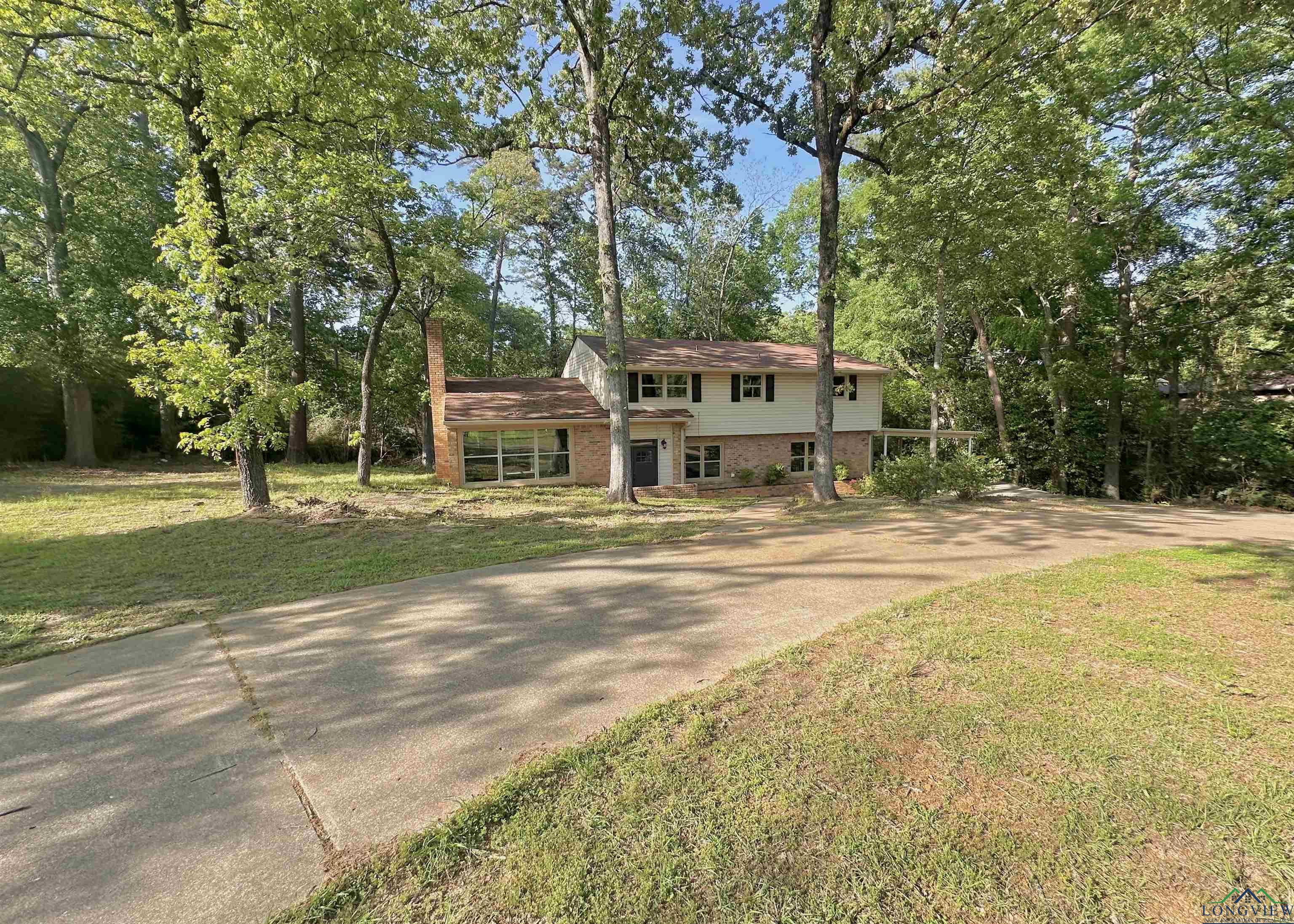 Image 1: Traditional-style house featuring a front yard, a chimney, brick siding, and driveway, Front Of Structure