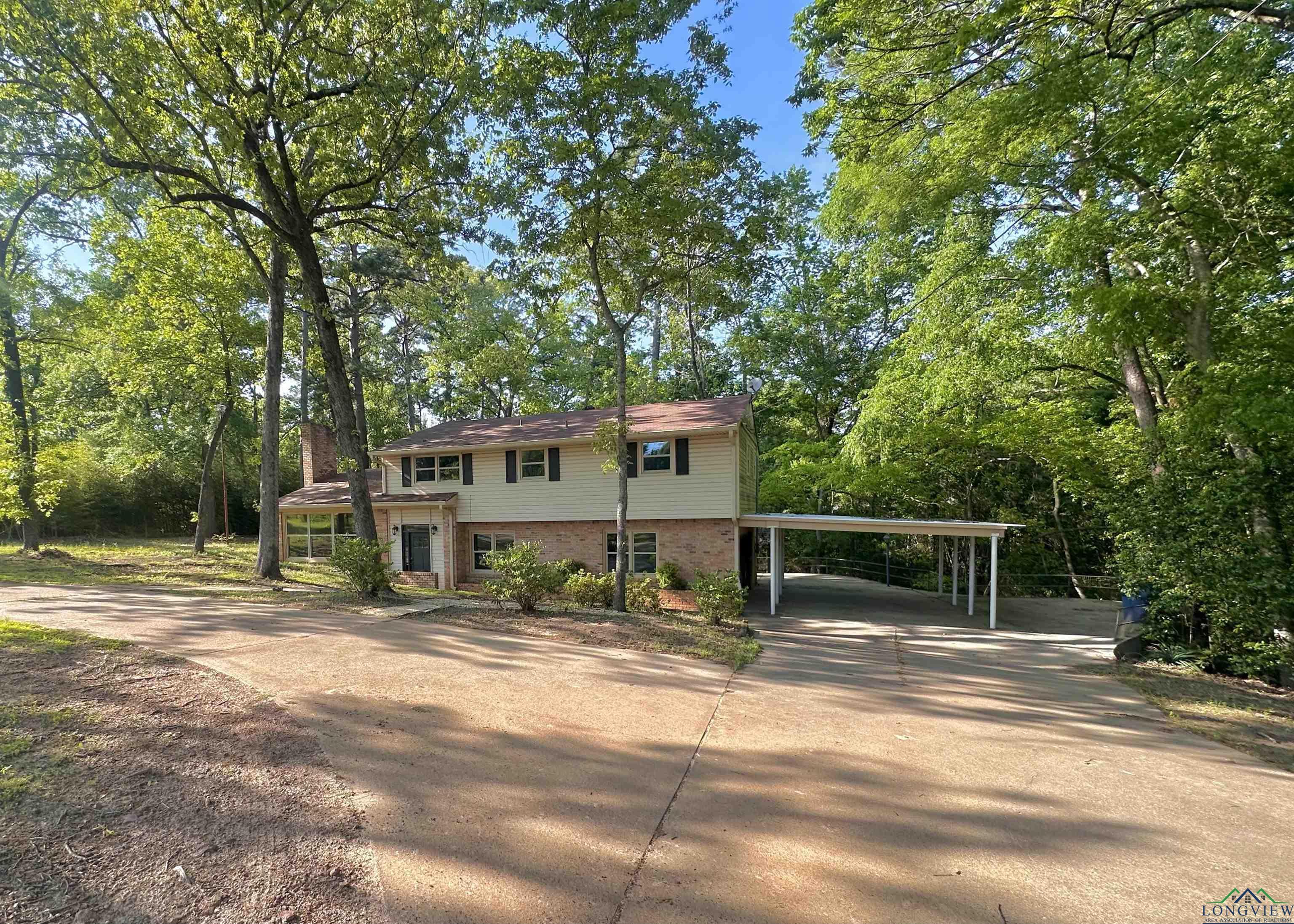 Image 1: View of front of home featuring brick siding, driveway, and a carport, Front Of Structure