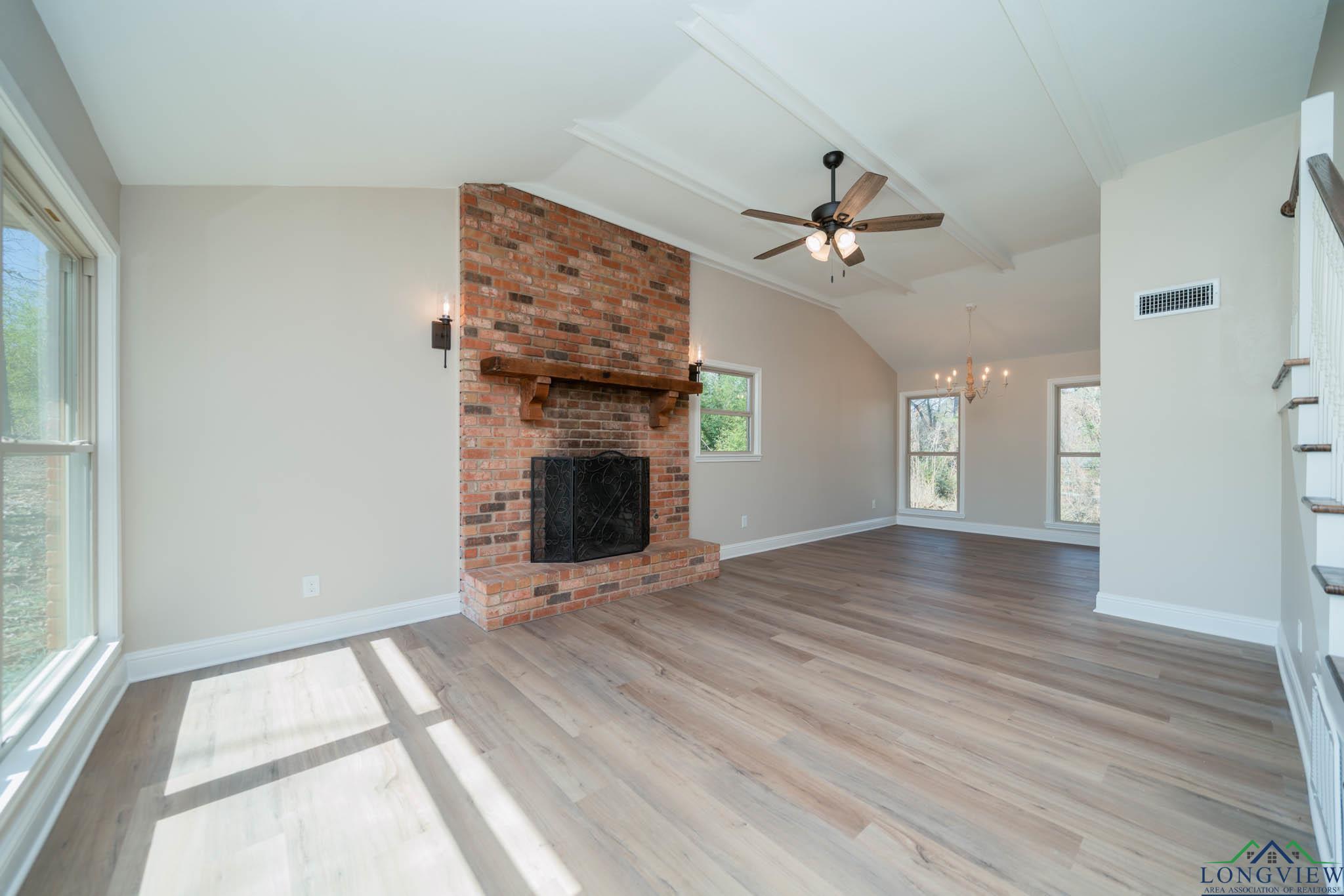 Image 2: Unfurnished living room with a fireplace, ceiling fan, light wood-style flooring, and a chandelier, Living Room