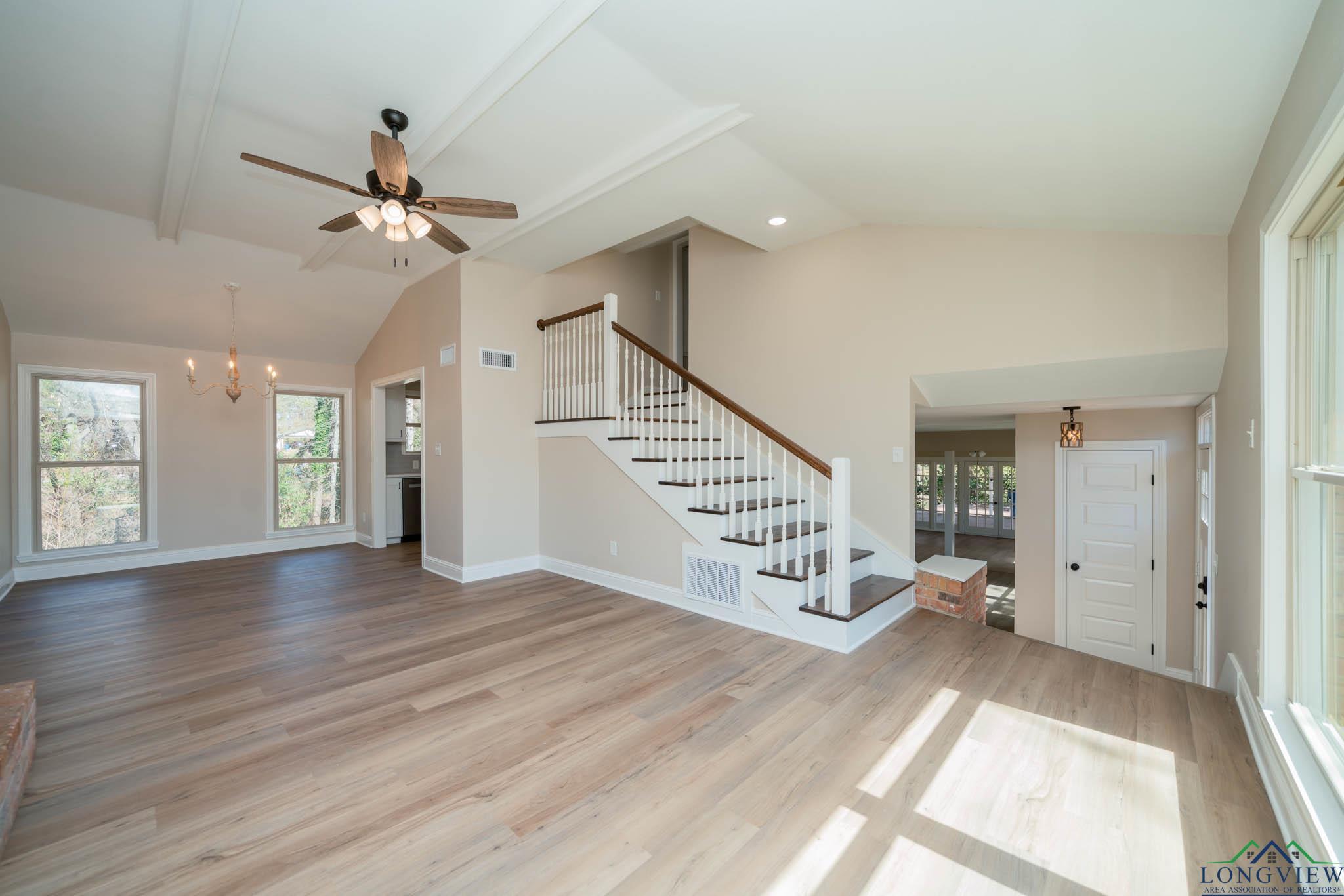 Image 3: Unfurnished living room with a chandelier, stairway, light wood-type flooring, plenty of natural light, and beam ceiling, Living Room
