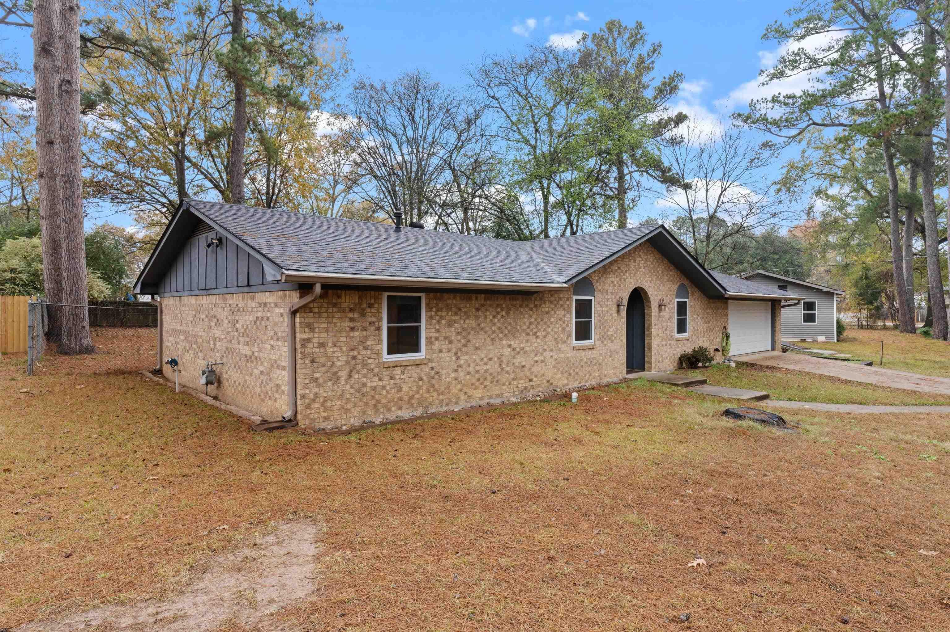 Image 1: View of front facade featuring brick siding, board and batten siding, a shingled roof, concrete driveway, and a garage, Front Of Structure