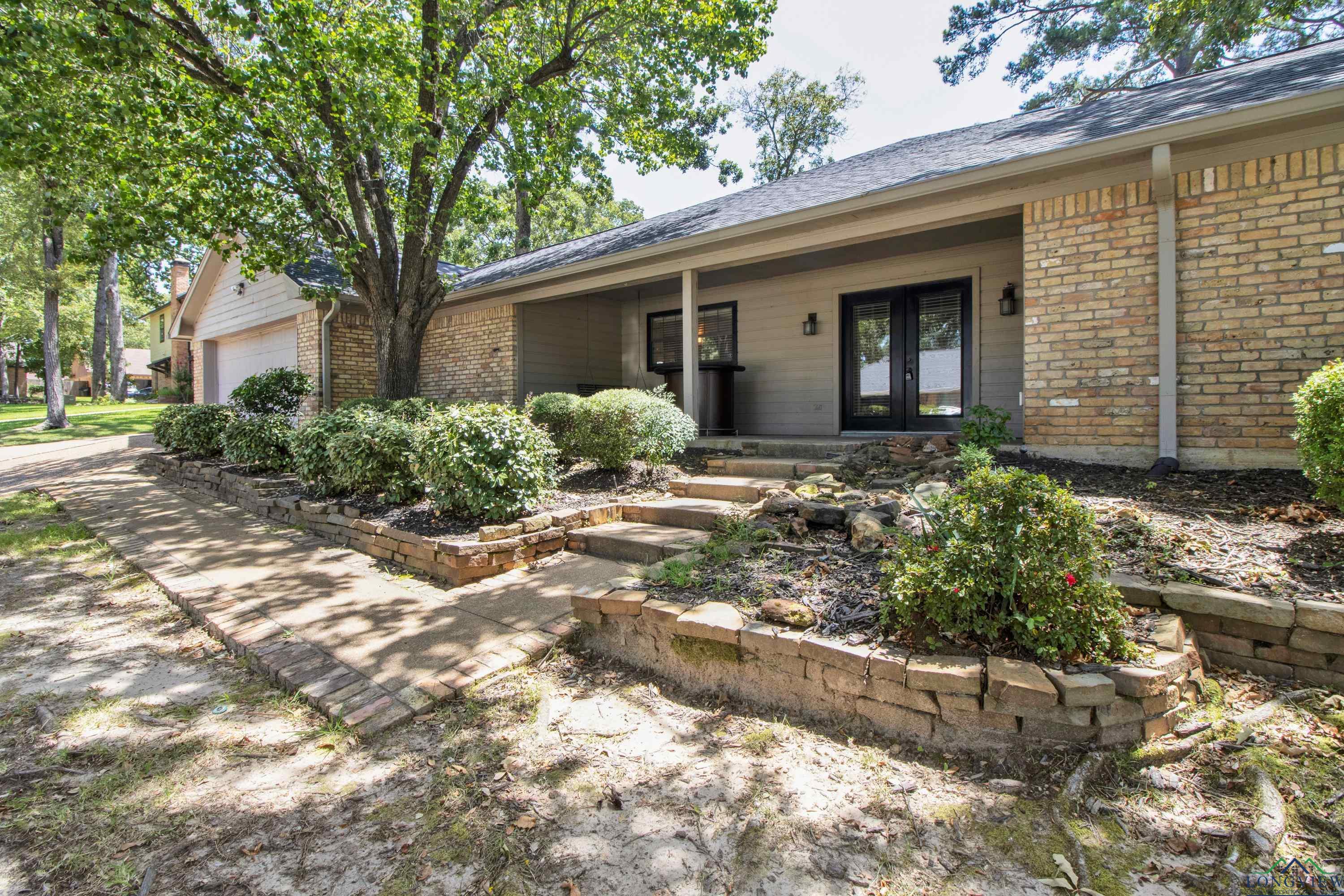 Image 2: View of front of house with french doors, an attached garage, brick siding, covered porch, and a shingled roof, Front Of Structure