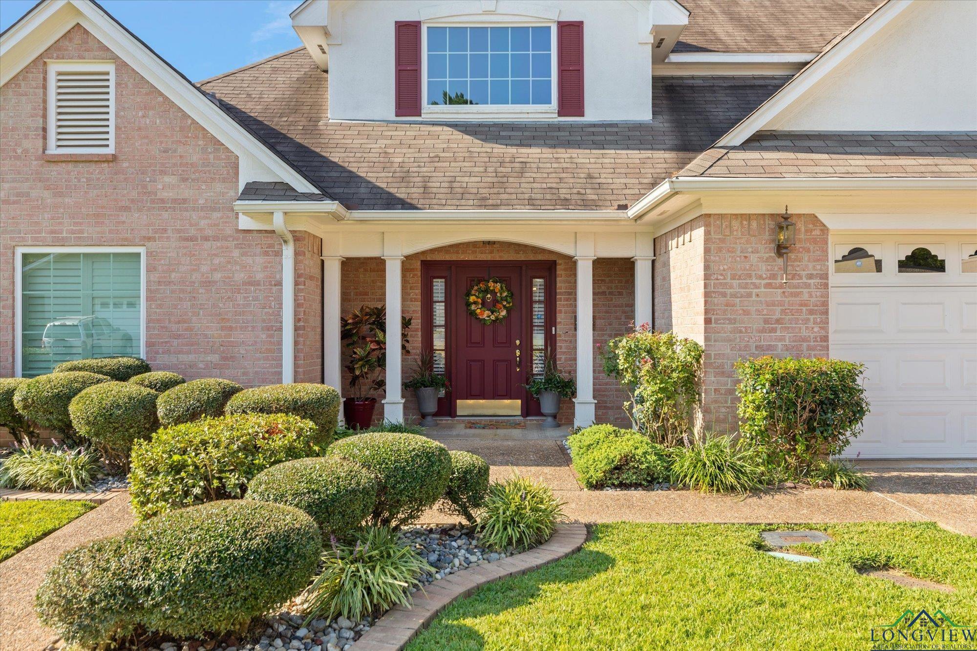 Image 1: View of exterior entry featuring covered porch, a shingled roof, brick siding, and a garage, Entry