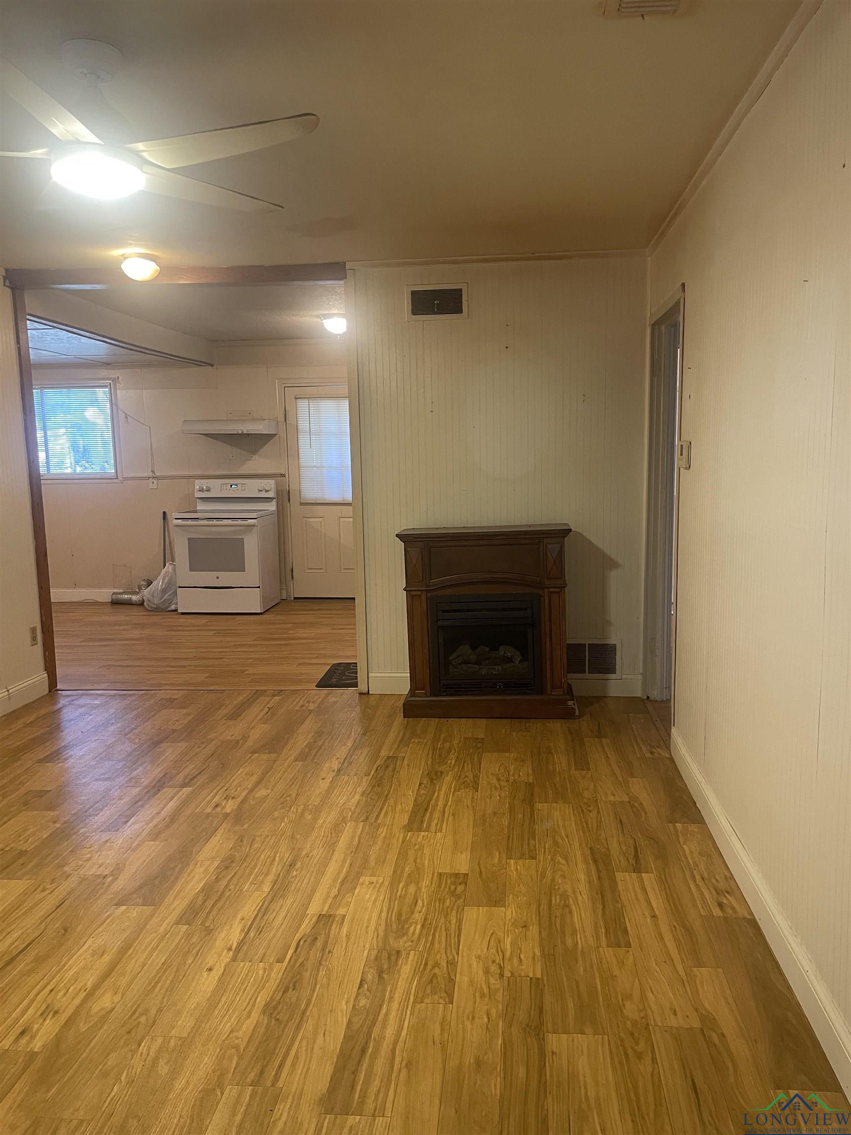 Image 3: Unfurnished living room featuring wood finished floors, a fireplace, and a ceiling fan, Living Room