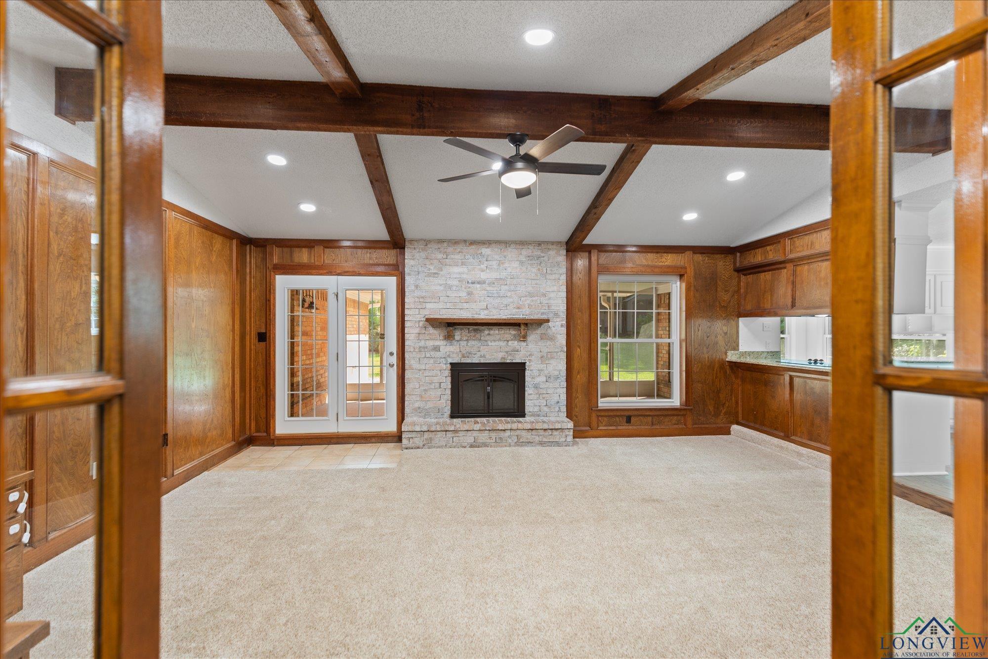 Image 3: Unfurnished living room with wooden walls, recessed lighting, light carpet, a fireplace, and a ceiling fan, Living Room