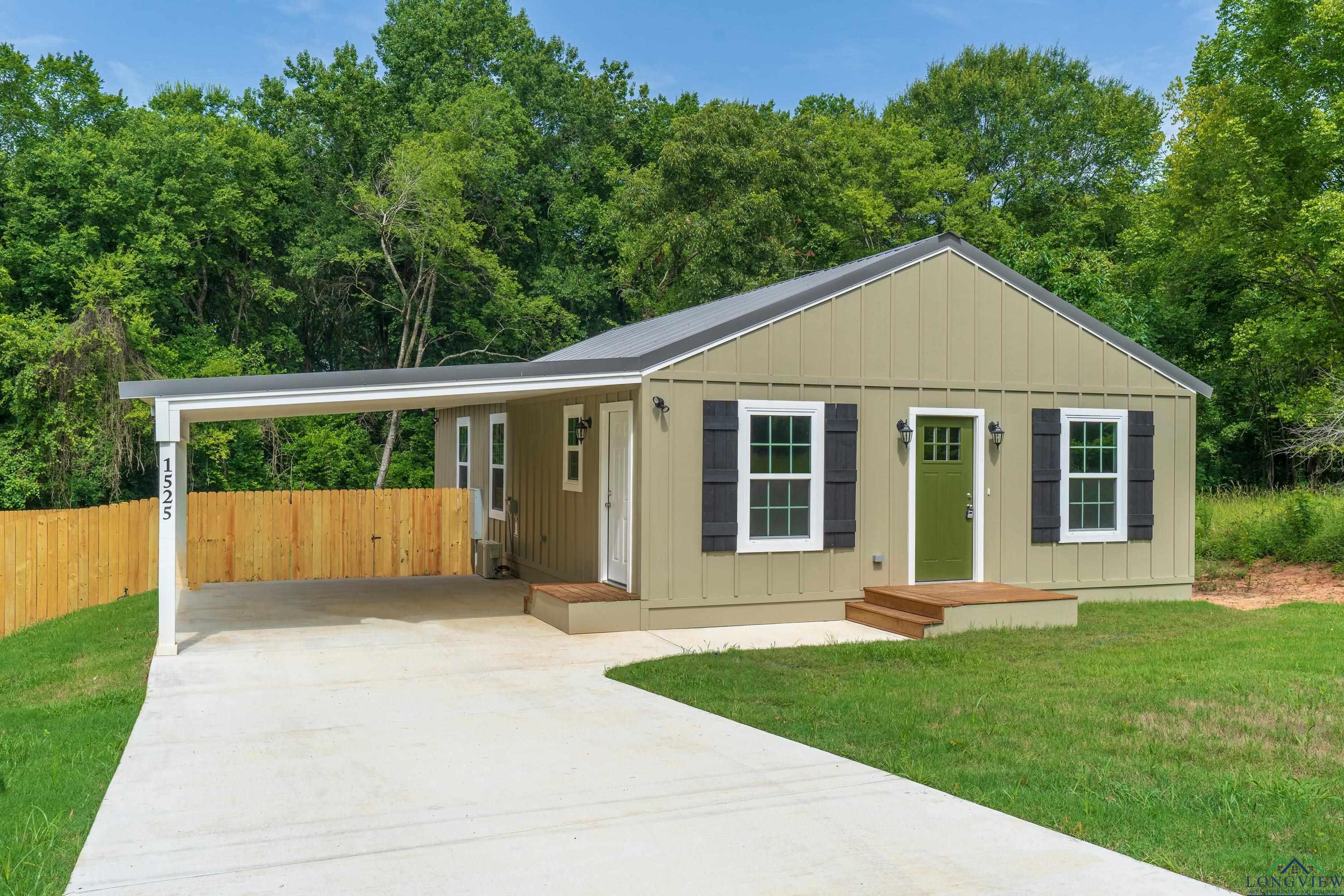 Image 1: View of front of home with board and batten siding, concrete driveway, and a carport, Front Of Structure