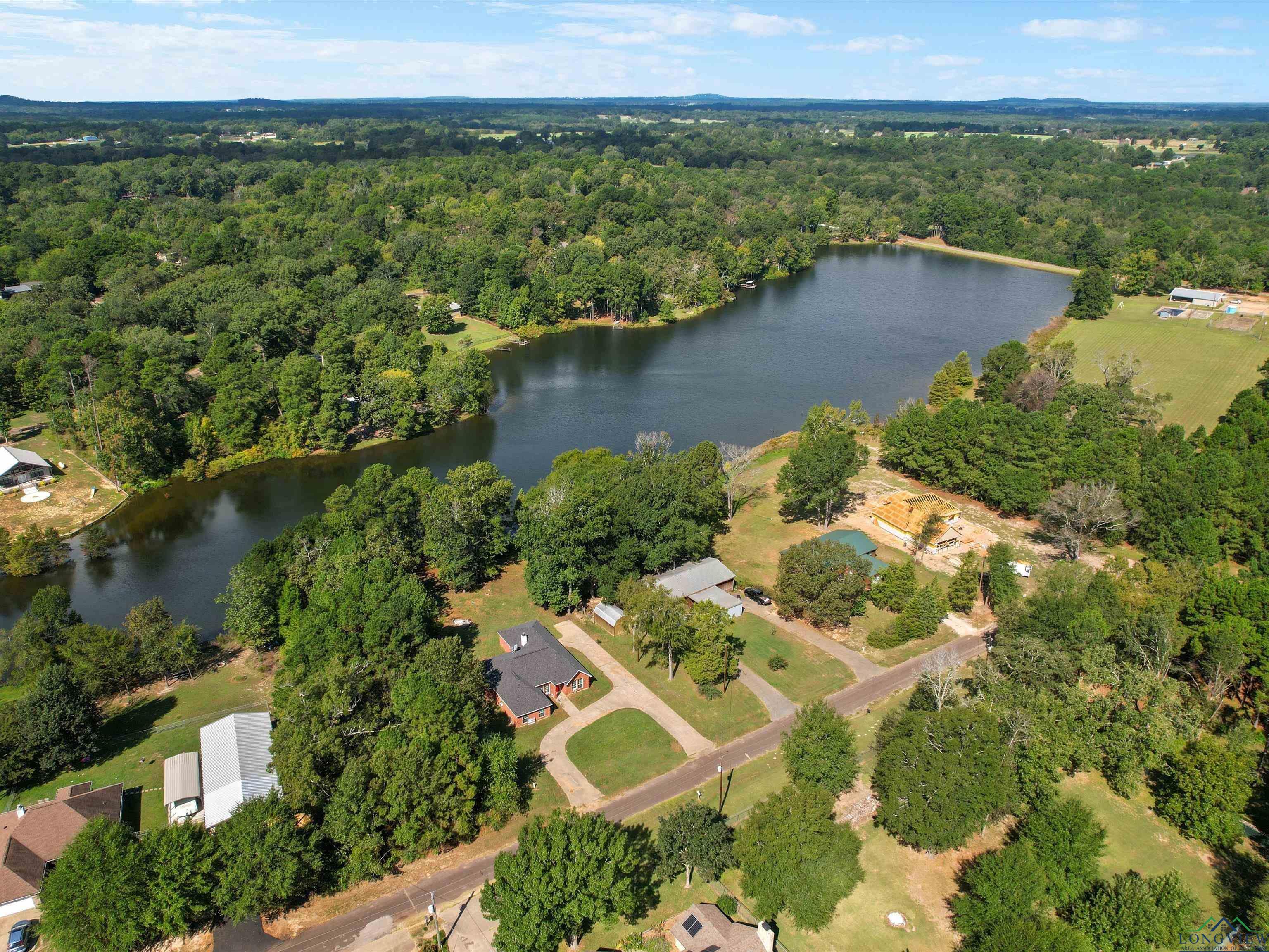 Image 3: Aerial view of property's location featuring a nearby body of water and a heavily wooded area, Aerial View