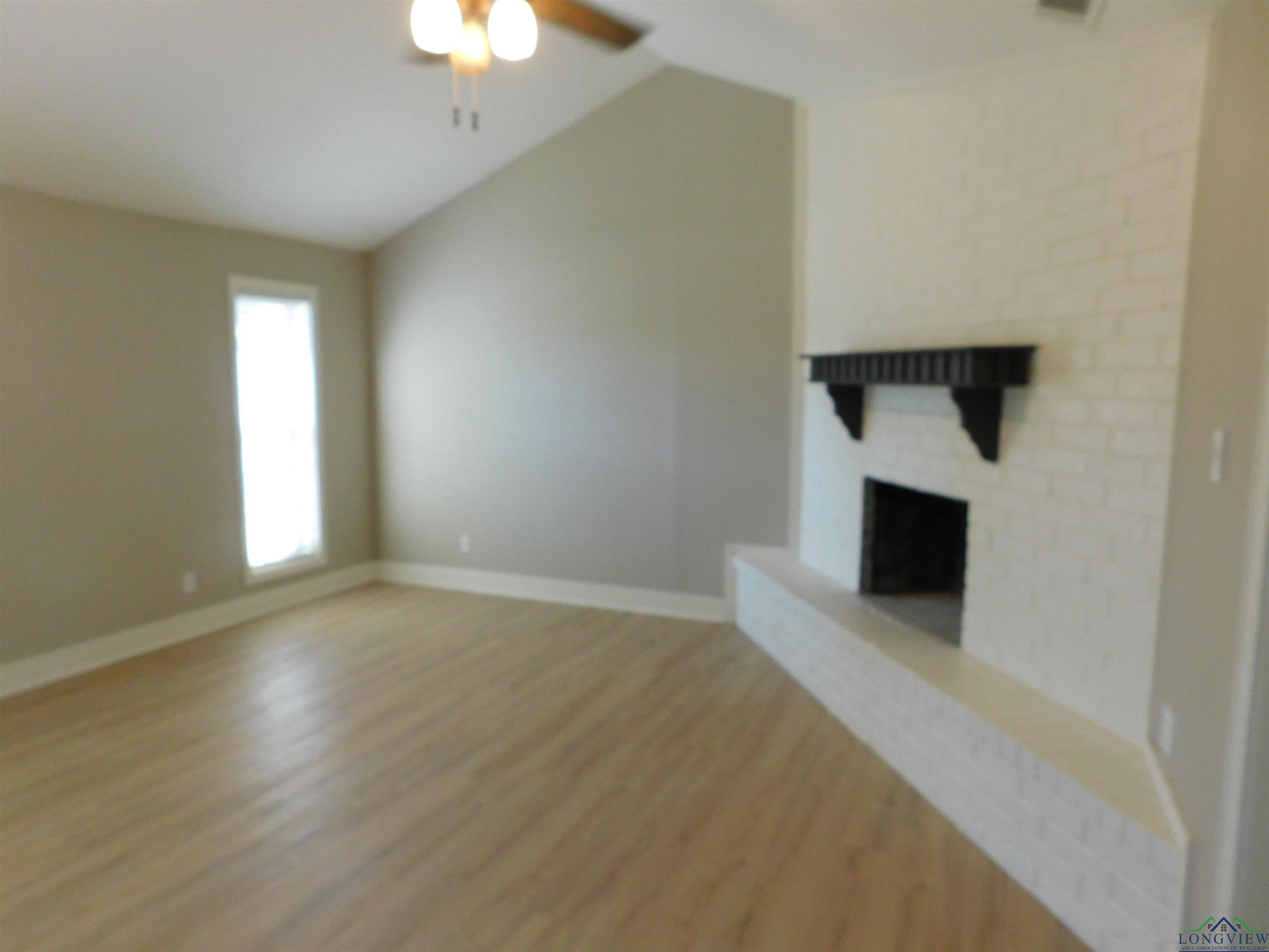 Image 1: Unfurnished living room with lofted ceiling, light wood-style floors, a fireplace, and a ceiling fan, Living Room