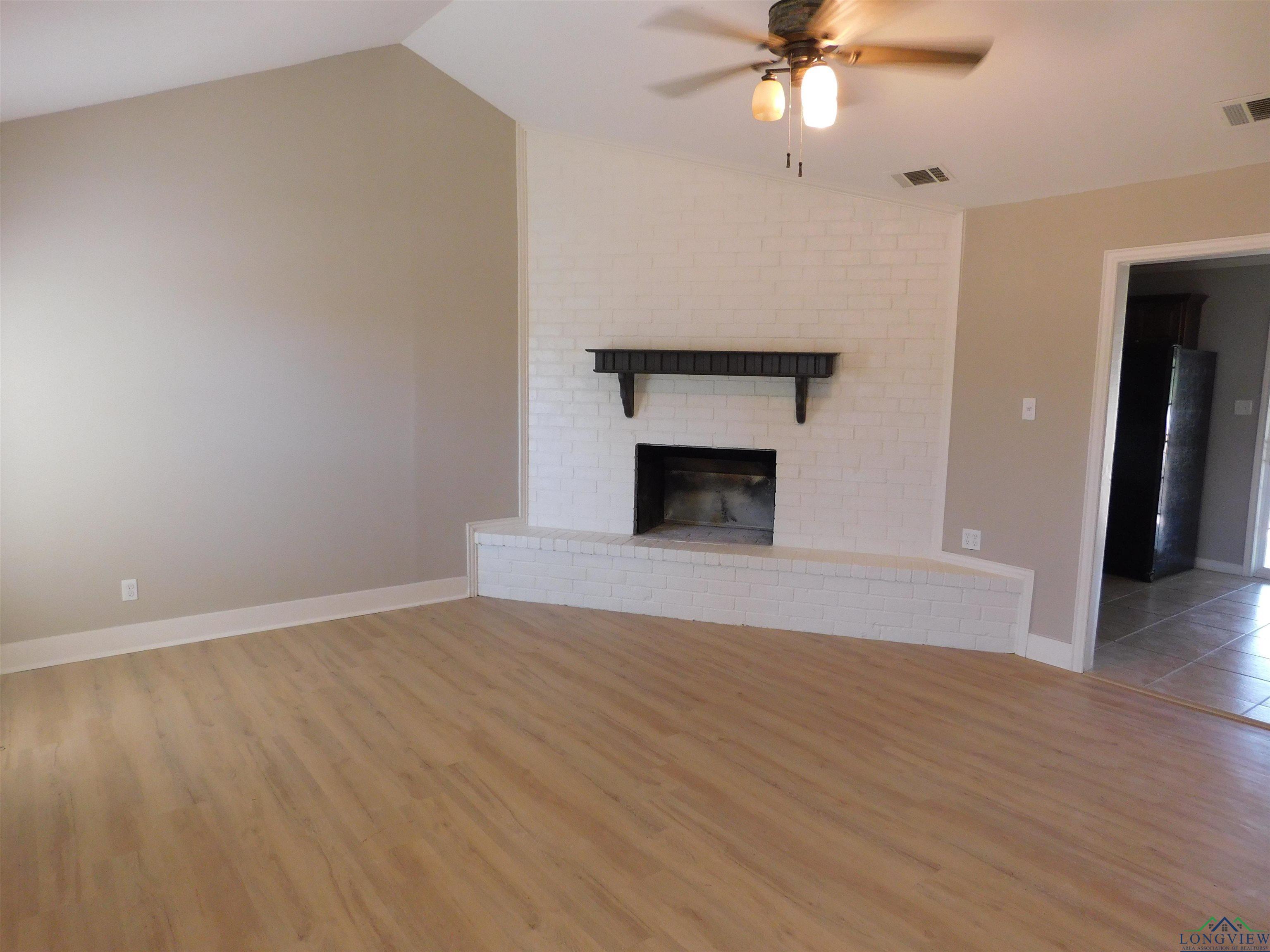 Image 2: Unfurnished living room with vaulted ceiling, light wood-style flooring, ceiling fan, and a fireplace, Living Room