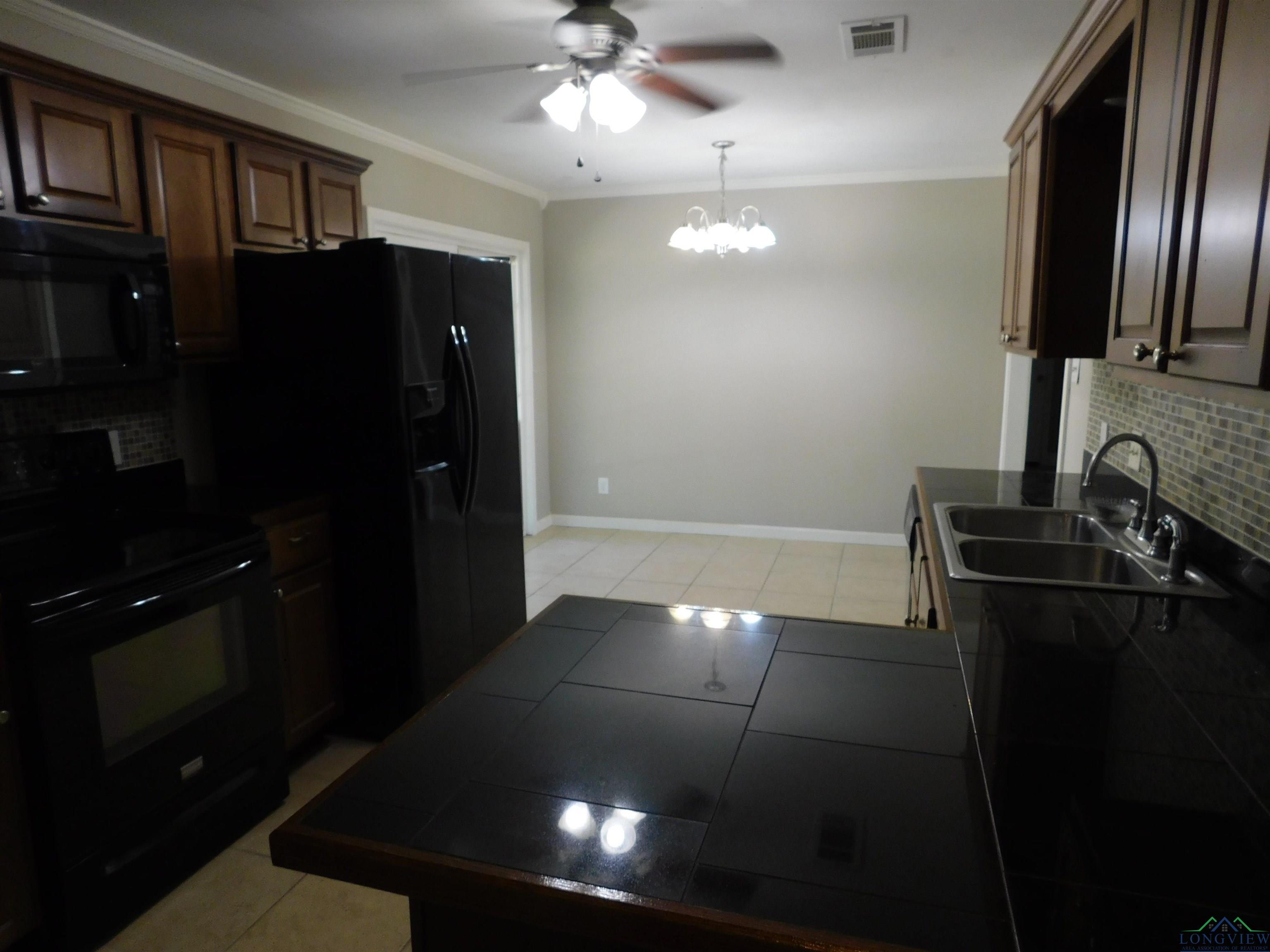 Image 3: Kitchen featuring tasteful backsplash, black appliances, light tile patterned floors, ornamental molding, and a chandelier, Kitchen