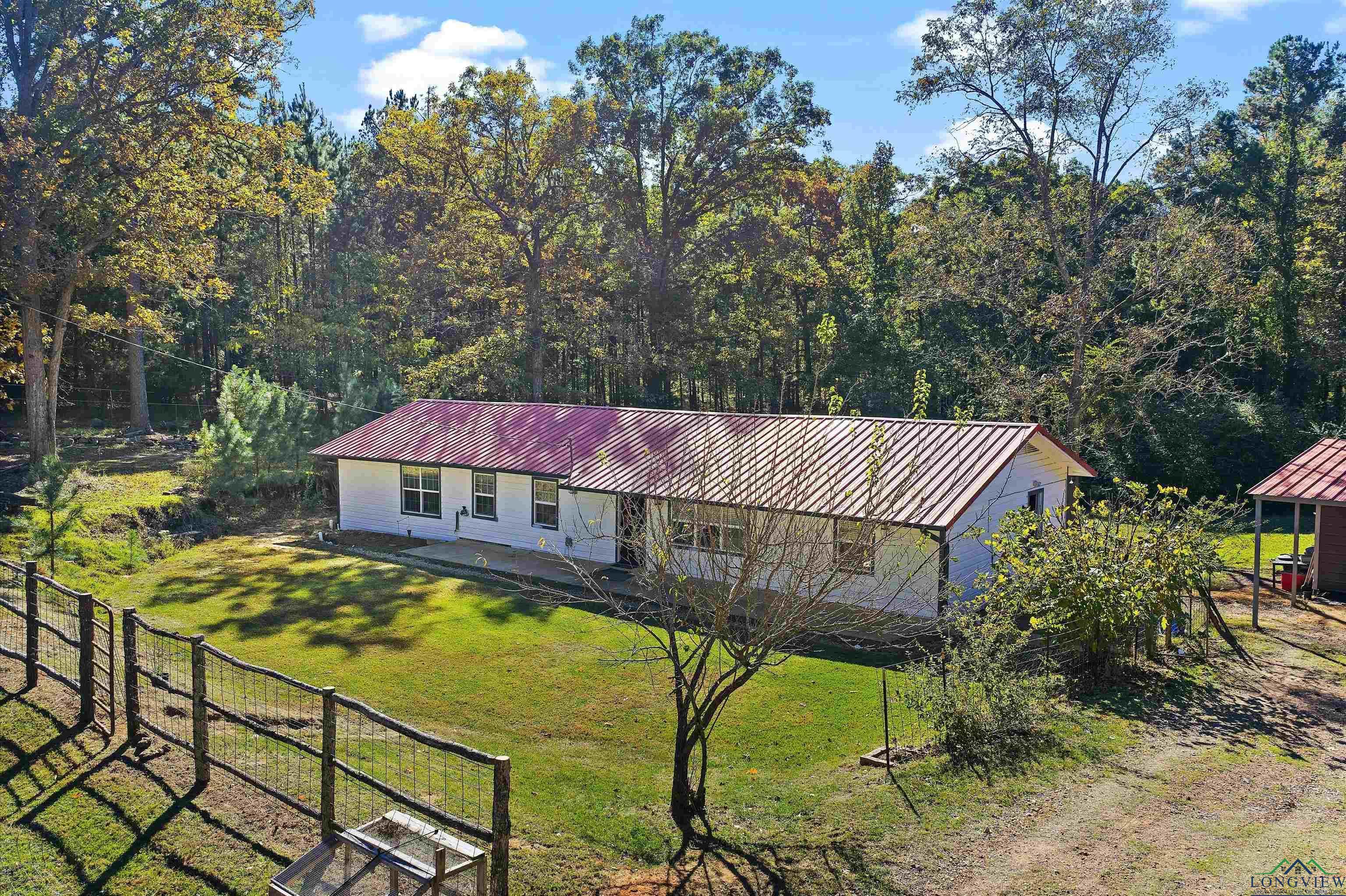 Image 1: View of front of home featuring a metal roof and a wooded view, Front Of Structure