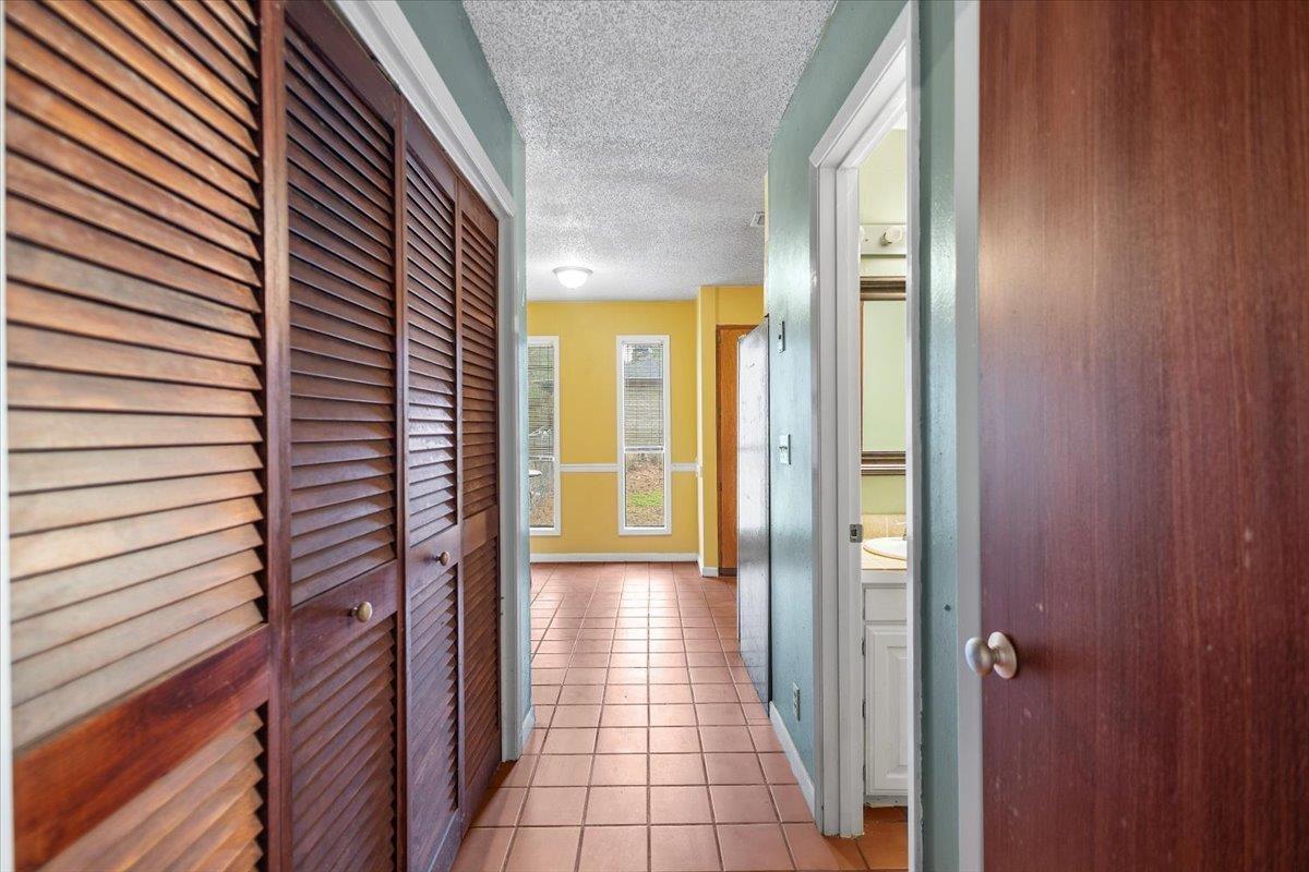 Image 3: Hall with a textured ceiling and light tile patterned floors, Hallway
