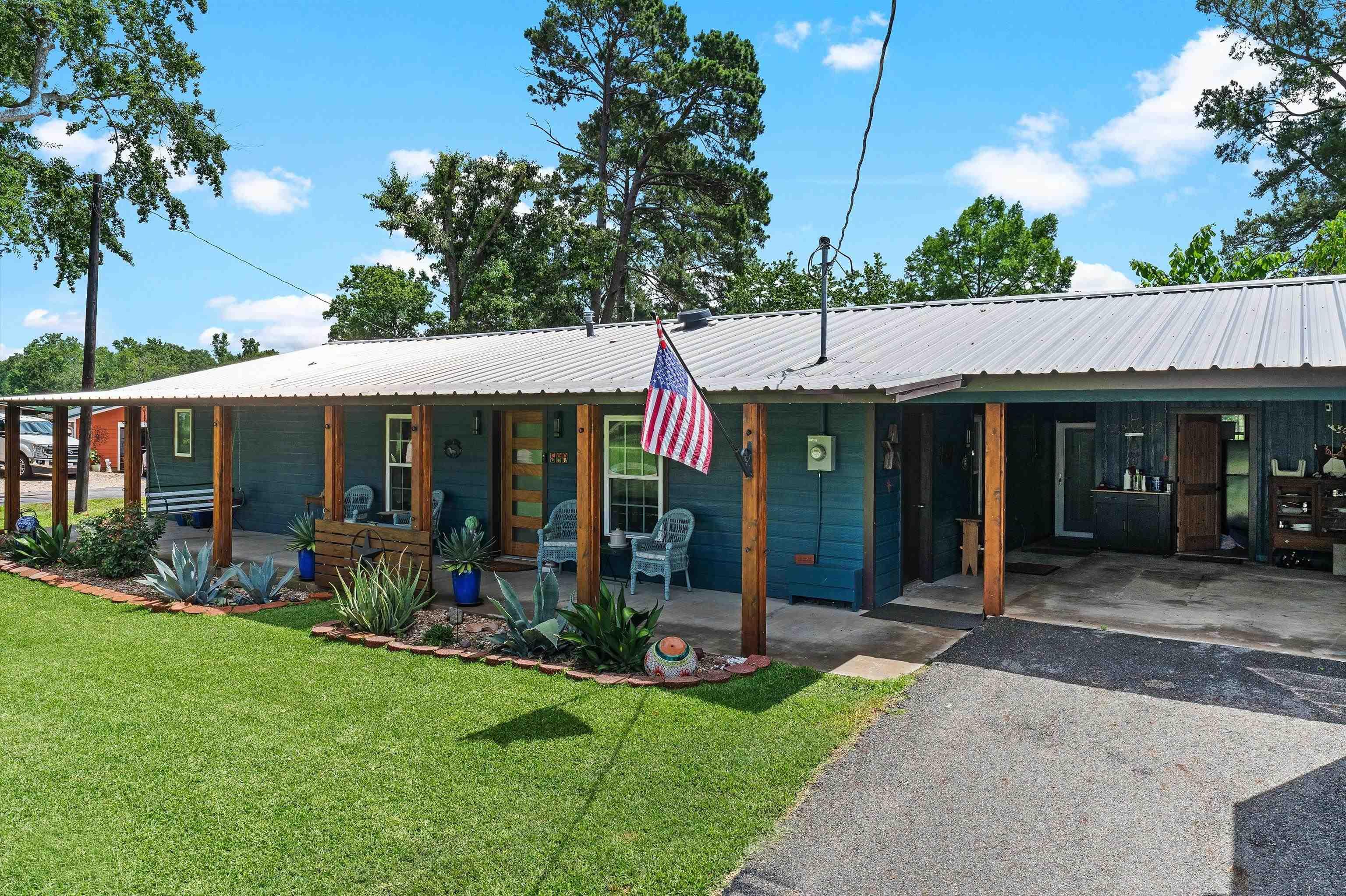 Image 0: View of front of house with a front lawn, a carport, driveway, a metal roof, and covered porch, Front Of Structure