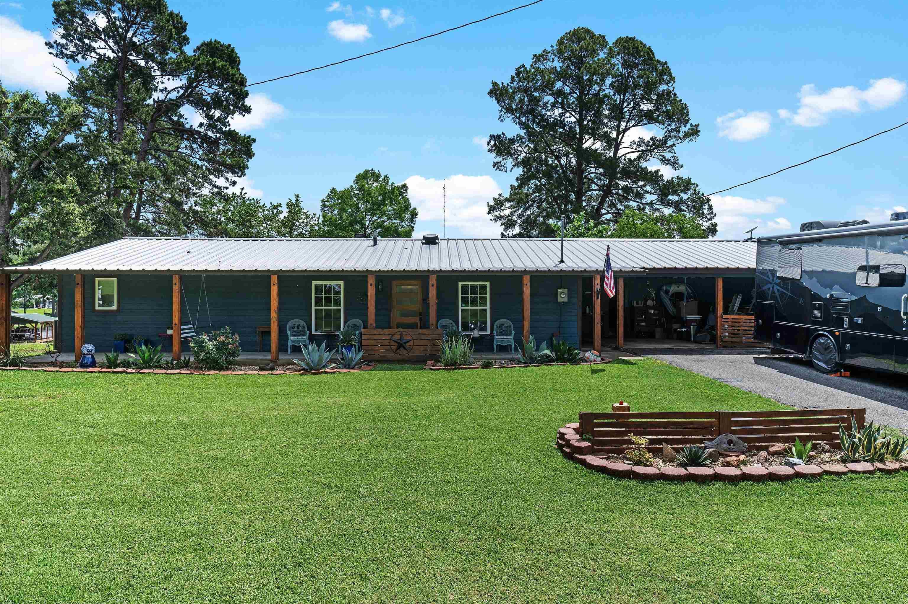 Image 3: Rear view of house featuring a lawn, a metal roof, a porch, an attached carport, and driveway, Back Of Structure