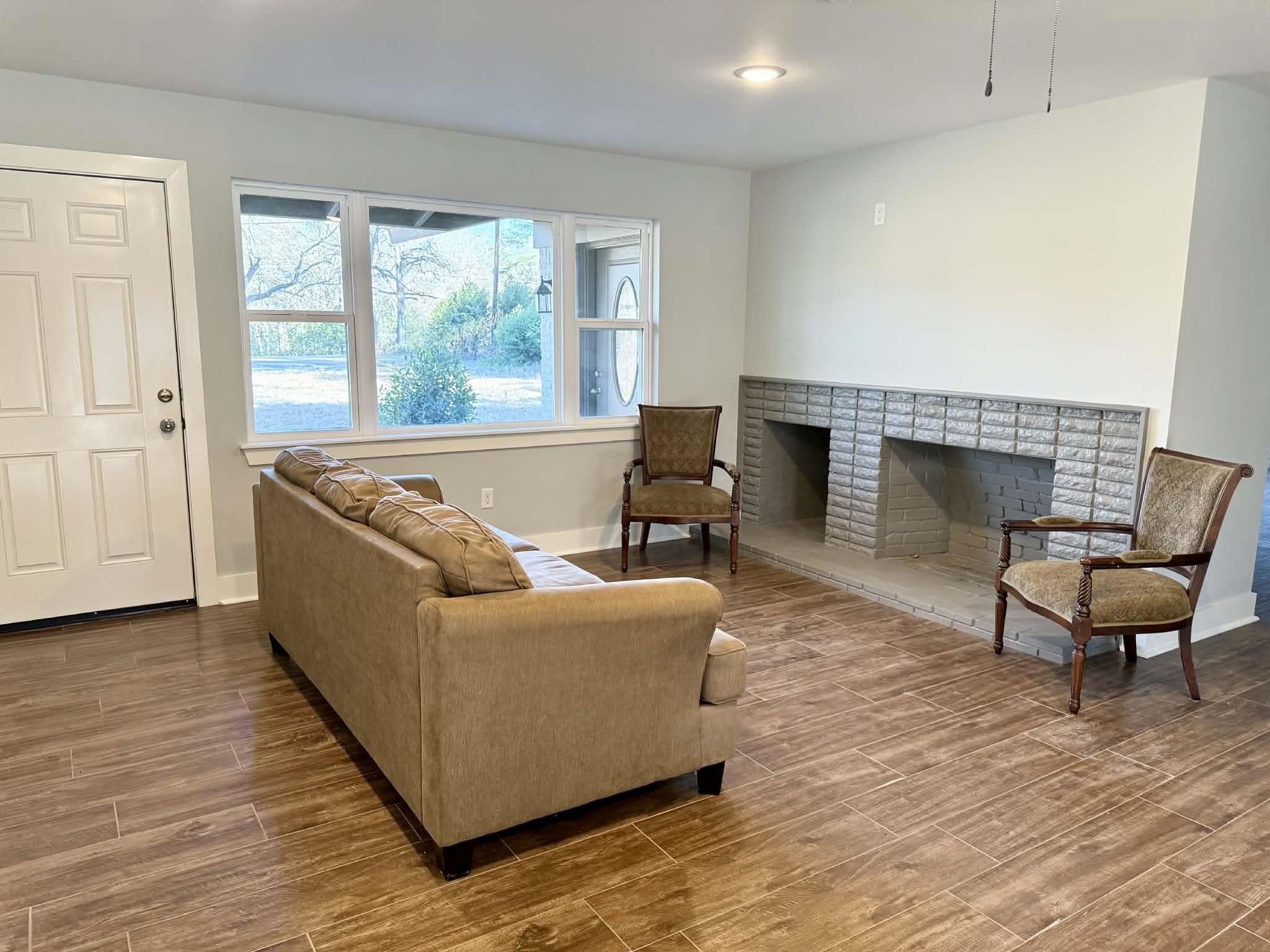 Image 3: Living area featuring a brick fireplace, wood tiled floors, and recessed lighting, Living Room