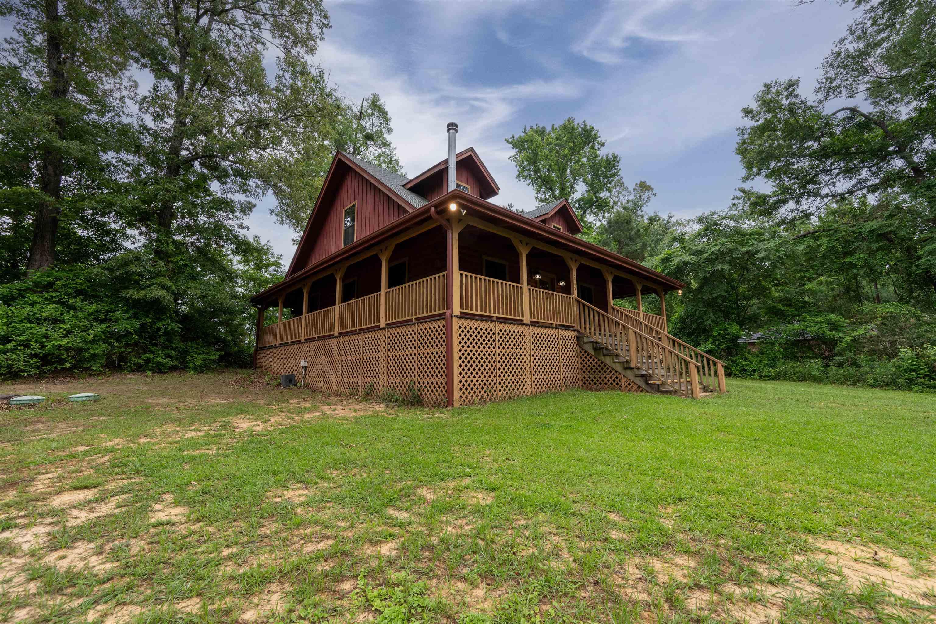 Image 3: Red-sided residence featuring a wrap-around porch with wood lattice skirting, Side Of Structure