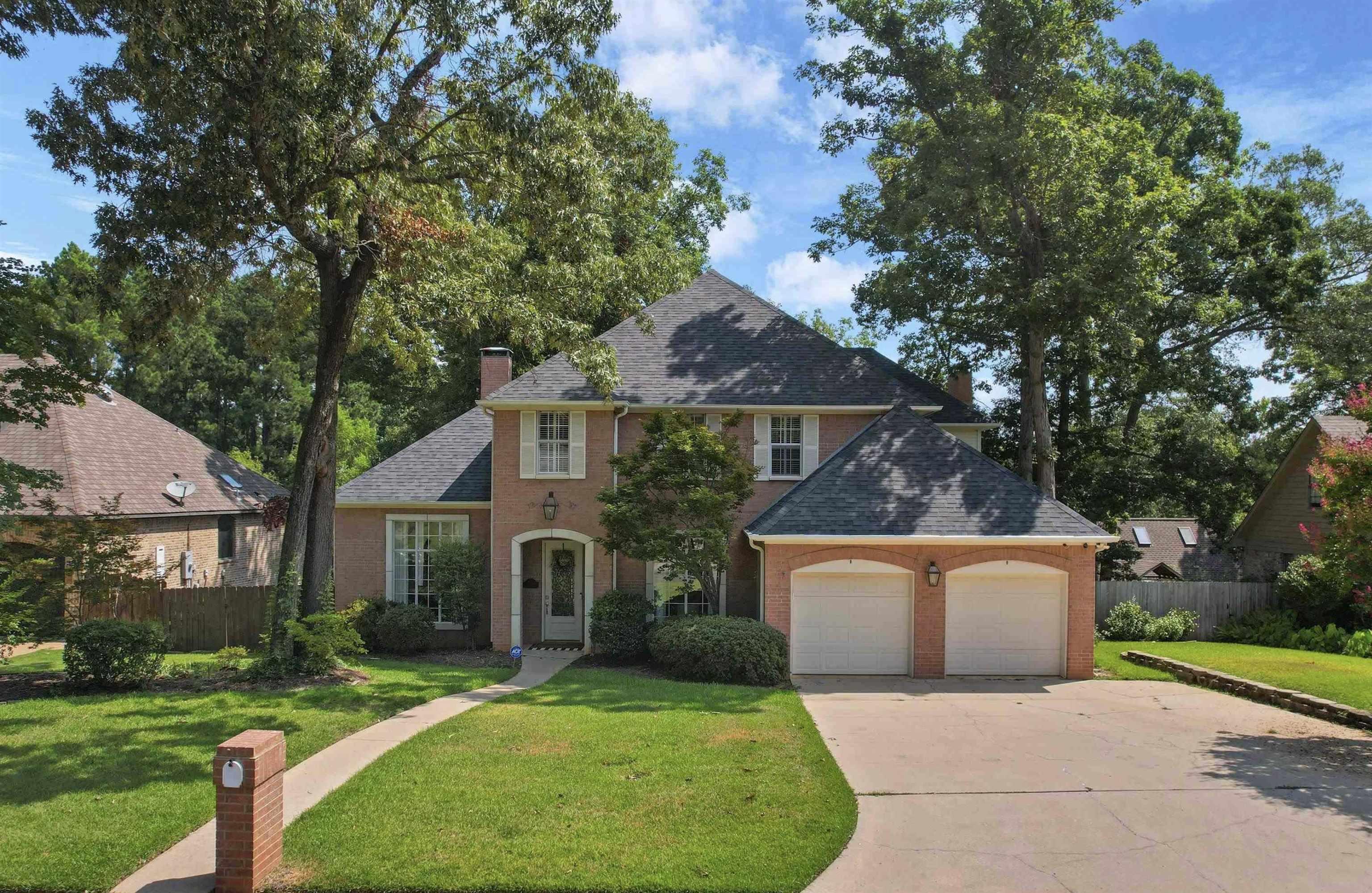Image 0: Brick two-story residence featuring a dark shingle roof, arched entry, and shuttered windows, Front Of Structure
