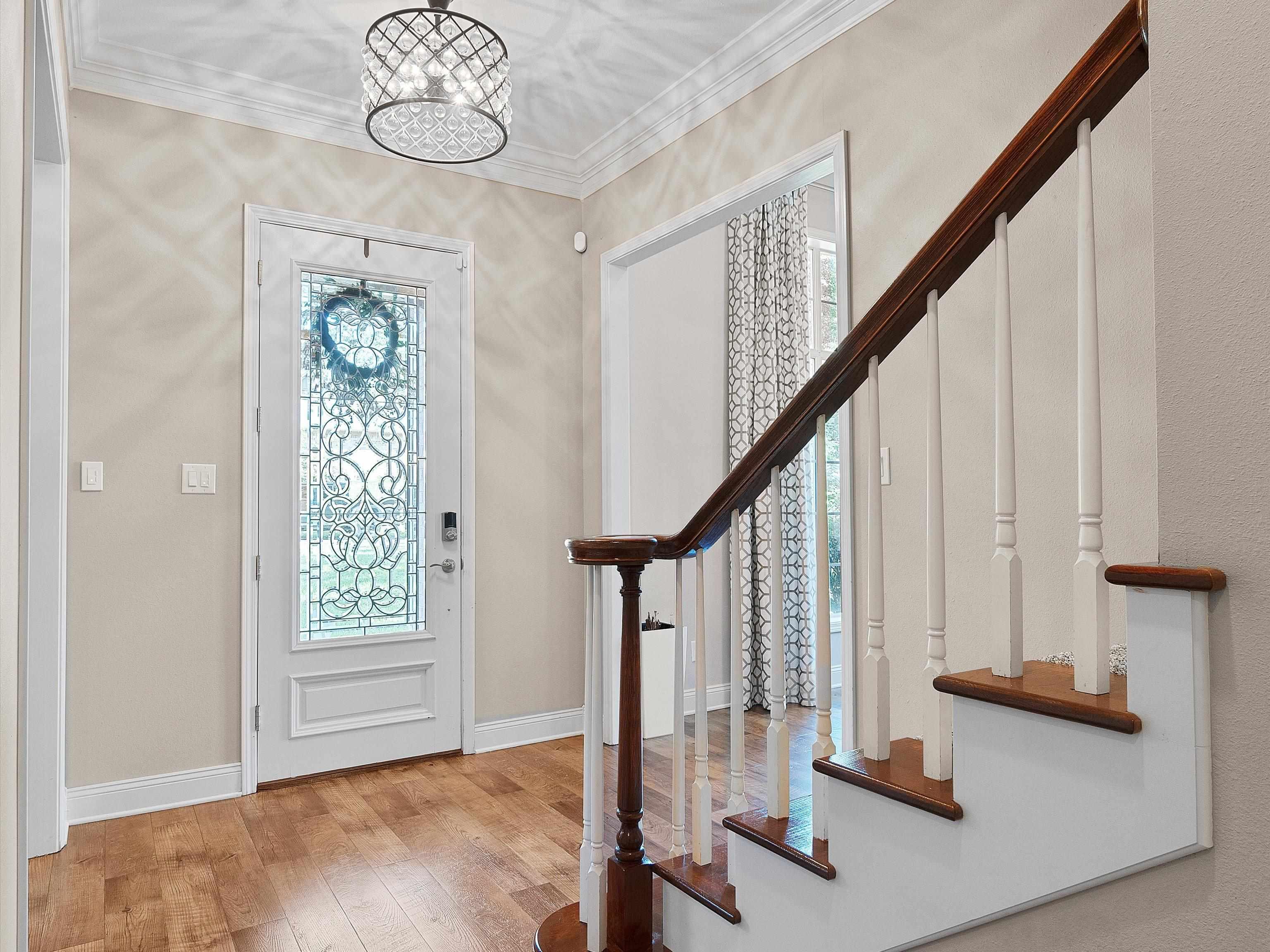 Image 2: Entryway featuring wood-finish flooring, a white front door with decorative leaded glass, and a modern drum chandelier, Entrance Foyer