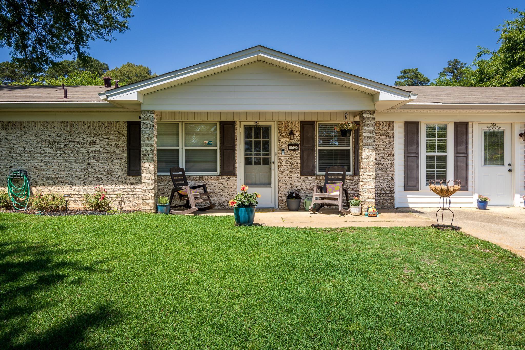 Image 1: Brick facade home featuring a covered front porch, white siding accents, and dark louvered shutters, Front Of Structure