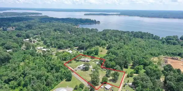 Image 1: Expansive property featuring multiple structures and significant tree coverage, Aerial View