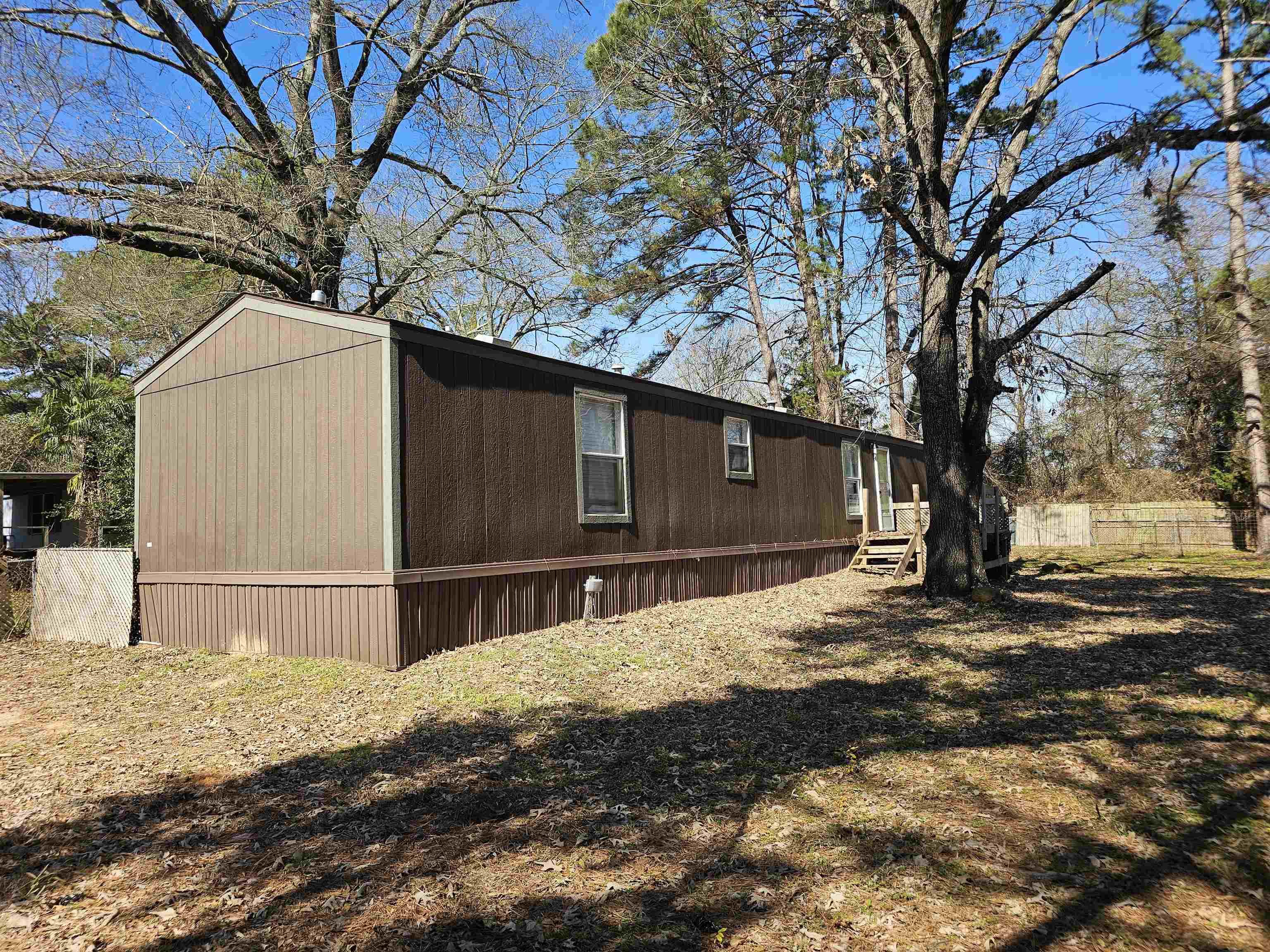 Image 1: Manufactured home featuring two-tone brown siding and white-framed windows, Side Of Structure