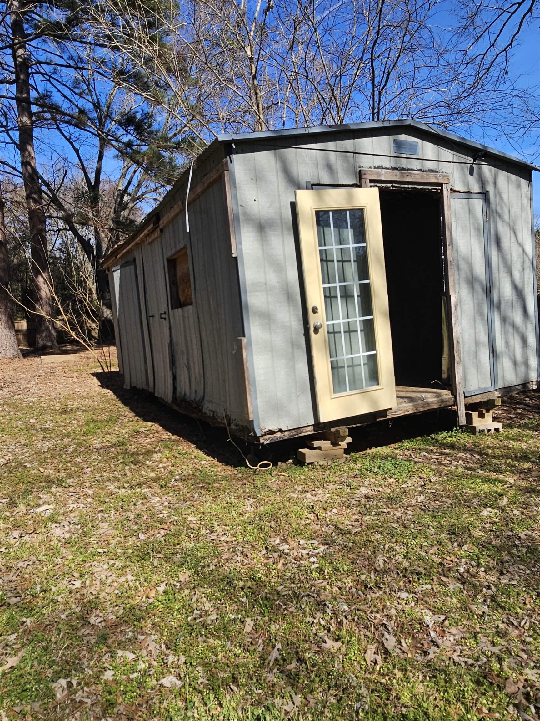 Image 2: Freestanding utility building with a metal roof and light-colored siding, Out Buildings
