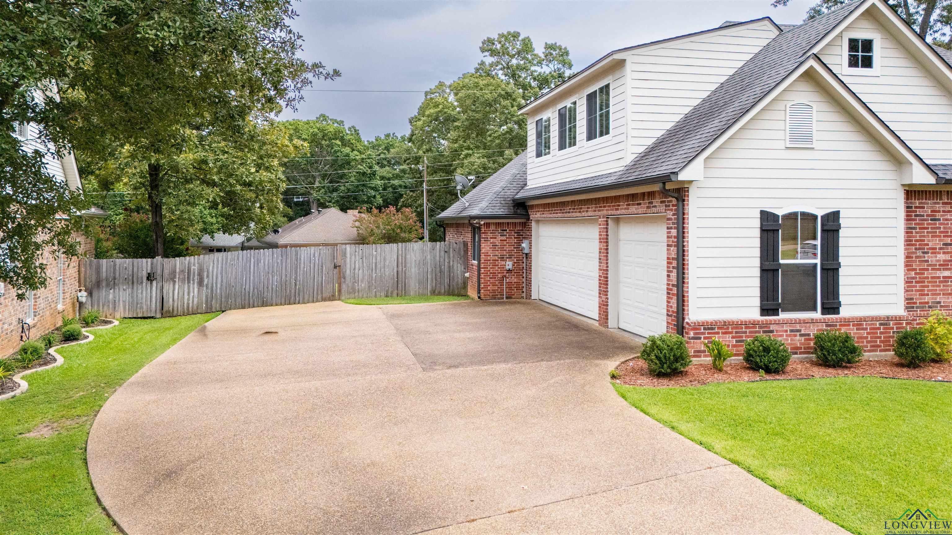 Image 1: View of property exterior featuring roof with shingles, a garage, brick siding, and concrete driveway, Side Of Structure