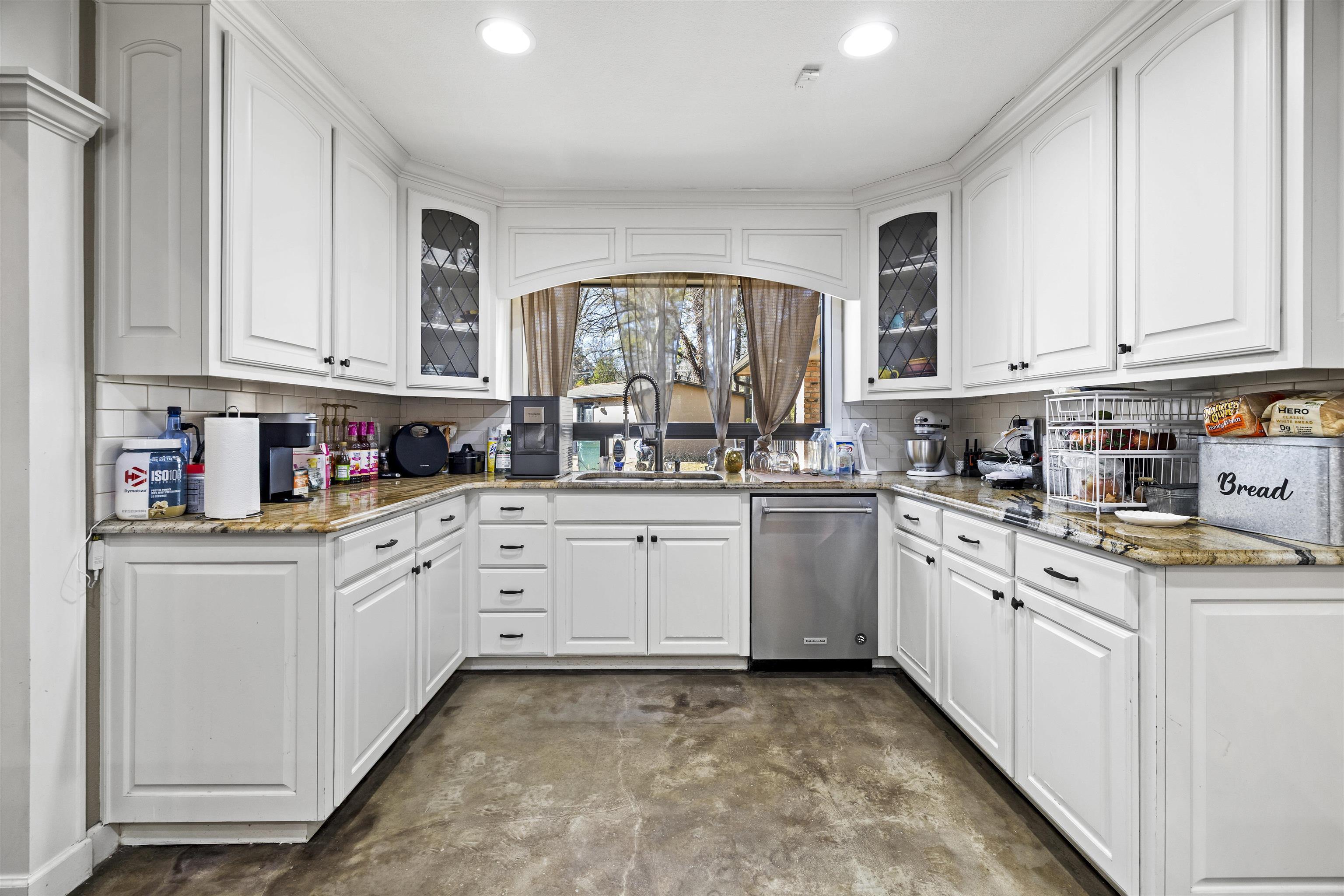 Image 2: Kitchen with light stone counters, finished concrete floors, and white cabinetry, Kitchen
