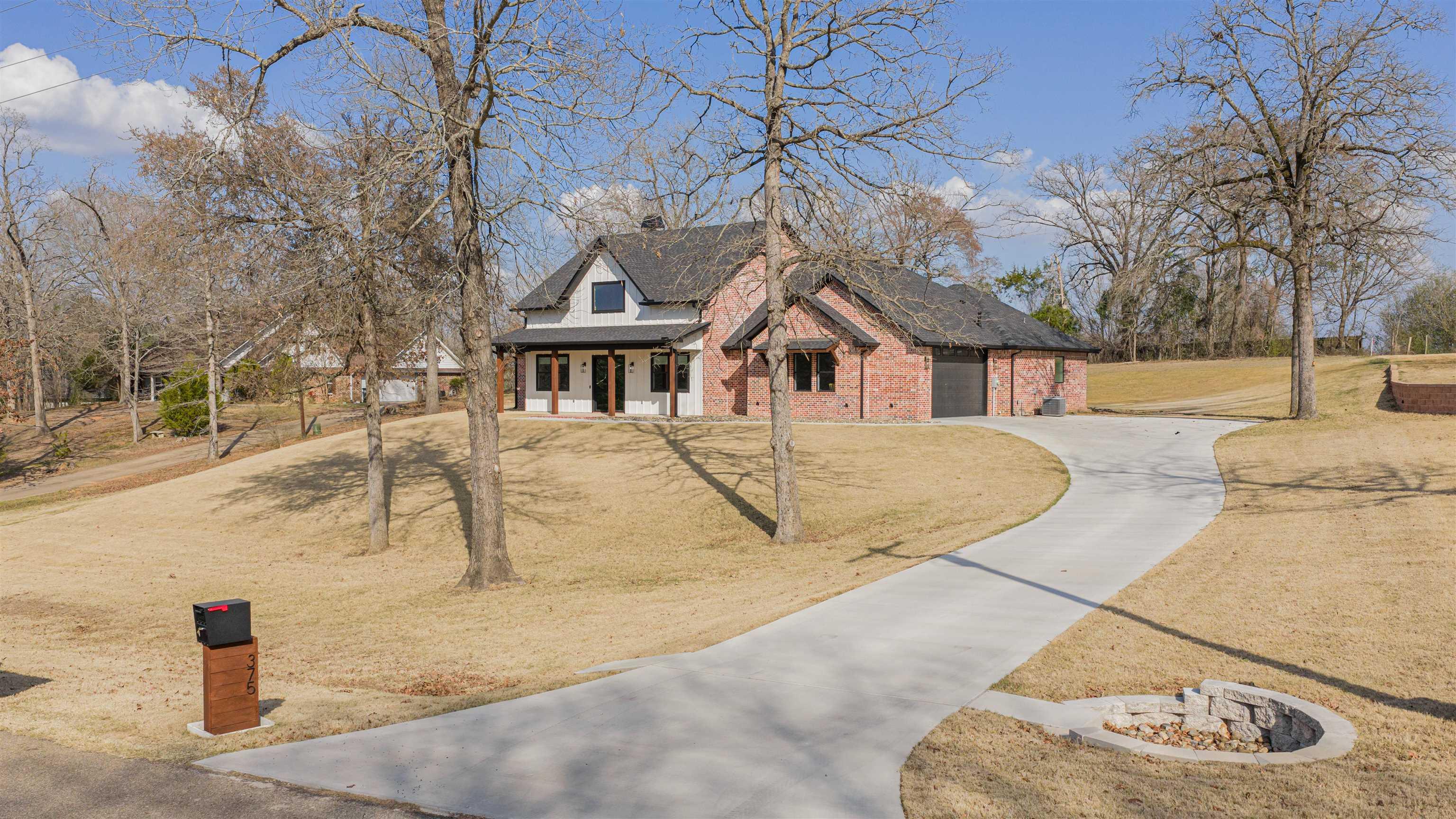 Image 2: Modern inspired farmhouse with concrete driveway, covered porch, brick siding, a front yard, and a garage, Front Of Structure