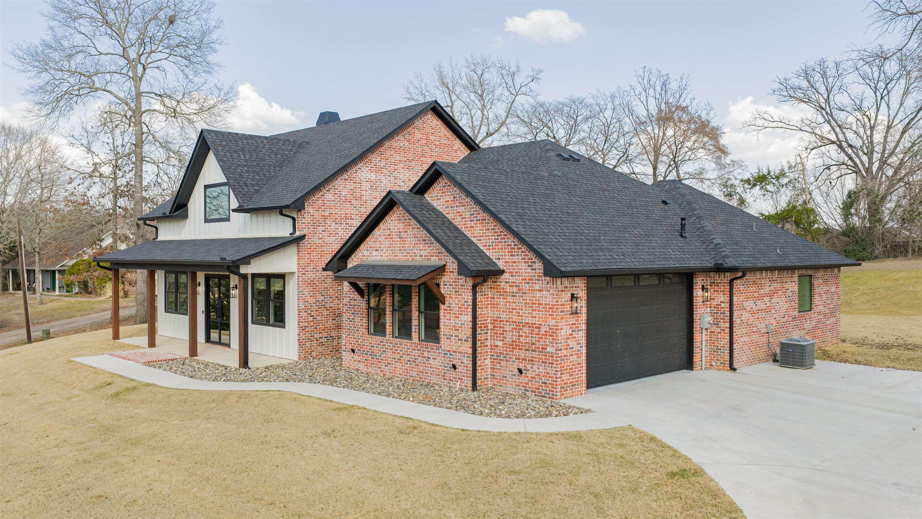 Image 3: View of front of house featuring a garage, driveway, a front lawn, brick siding, and covered porch, Front Of Structure