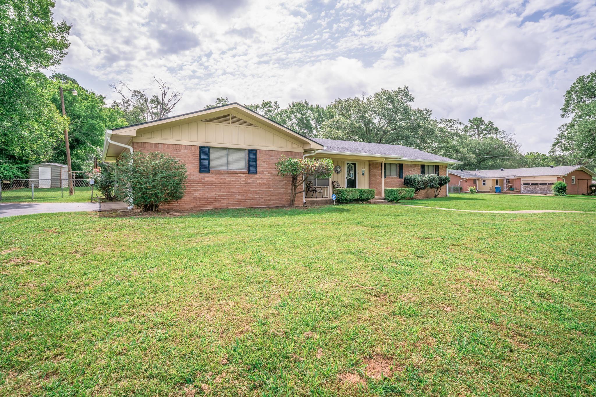 Image 0: Brick exterior residence featuring a front lawn, paved driveway, and mature landscaping, 704 N. Holly St.