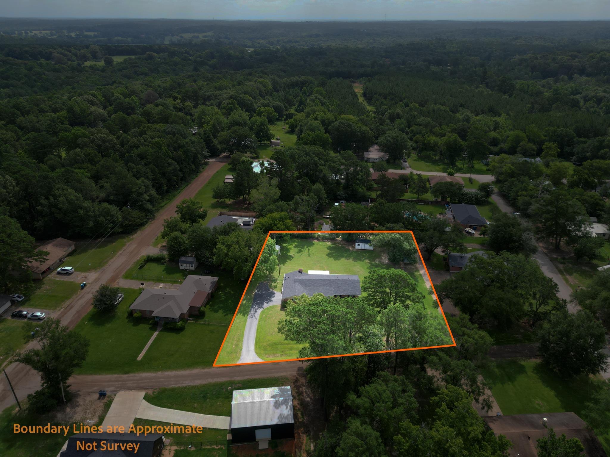 Image 2: Aerial property overview featuring a single-story residence with a gray roof, surrounded by mature trees and manicured lawns, Aerial View